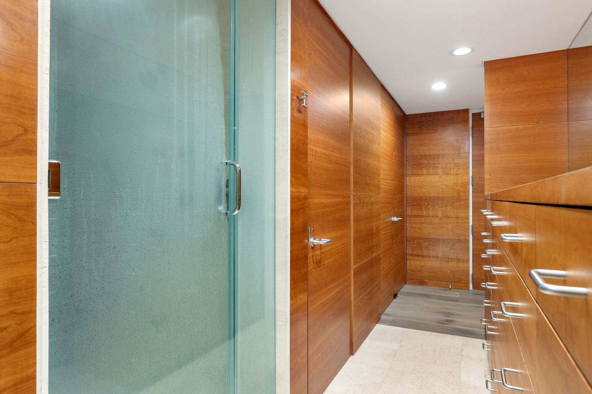 Glass walk-in shower with spa-style wood paneling.