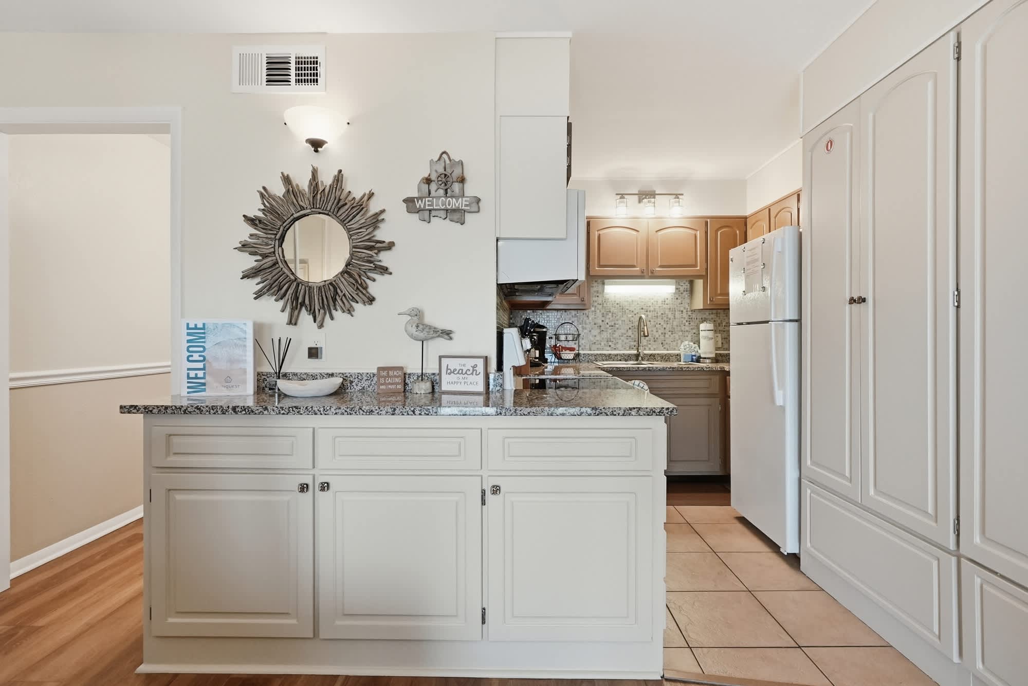The Summit 419 – Cozy kitchen with granite countertops, white cabinetry, and a decorative mirror. Sunlit space with modern appliances.