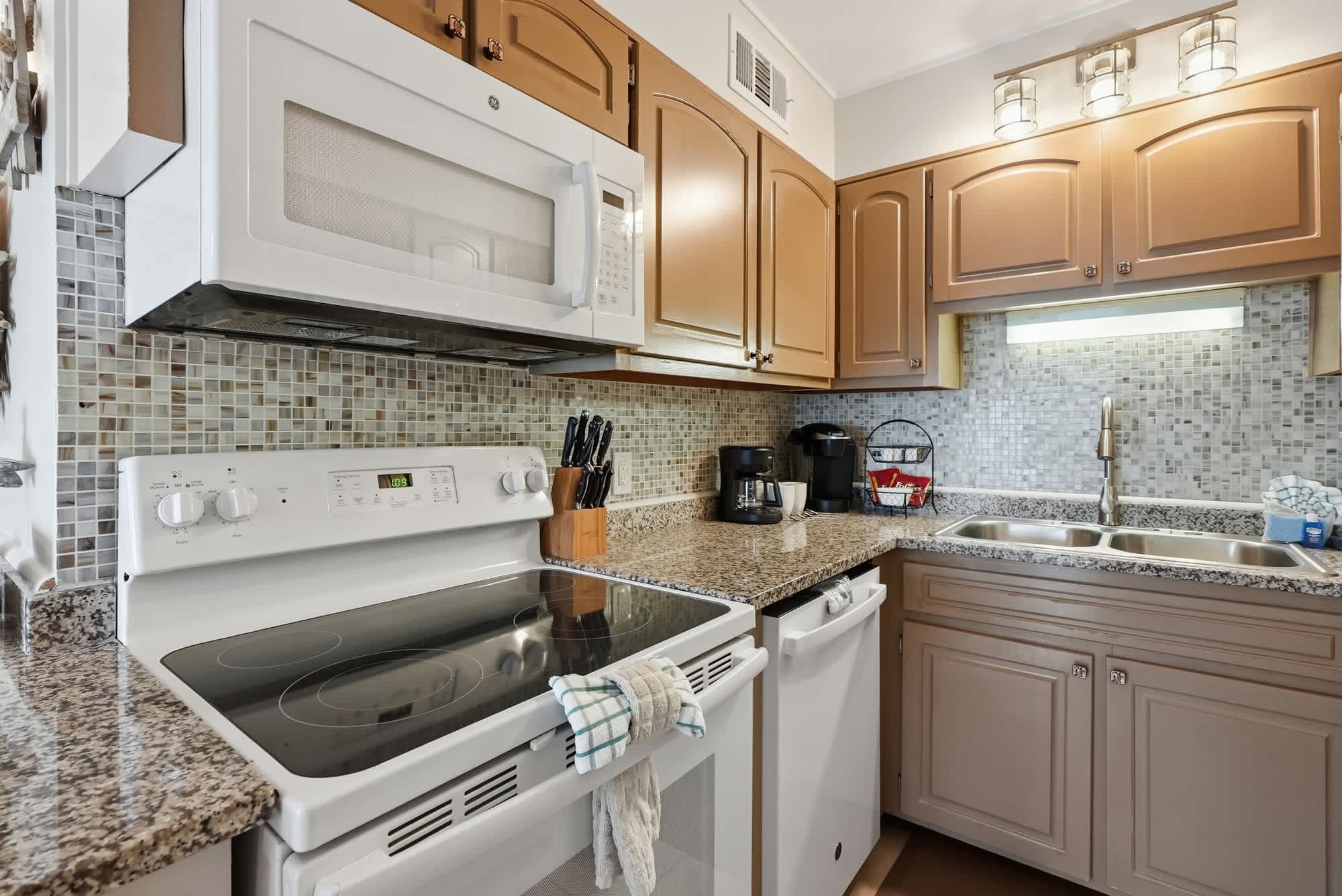 The Summit 419 – Compact kitchen featuring granite countertops, modern appliances, and mosaic tile backsplash.