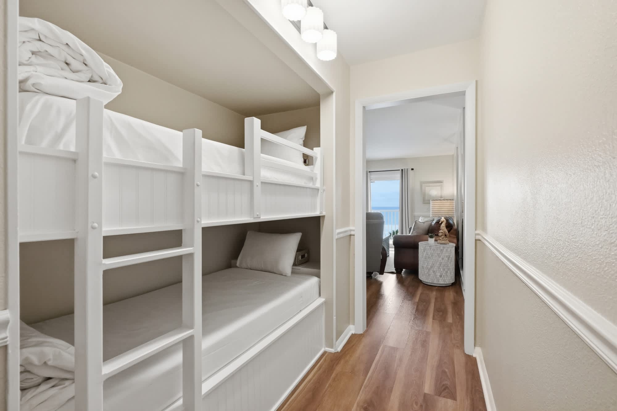 The Summit 419 – Bunk beds in a hallway with a view of a living room and ocean.
