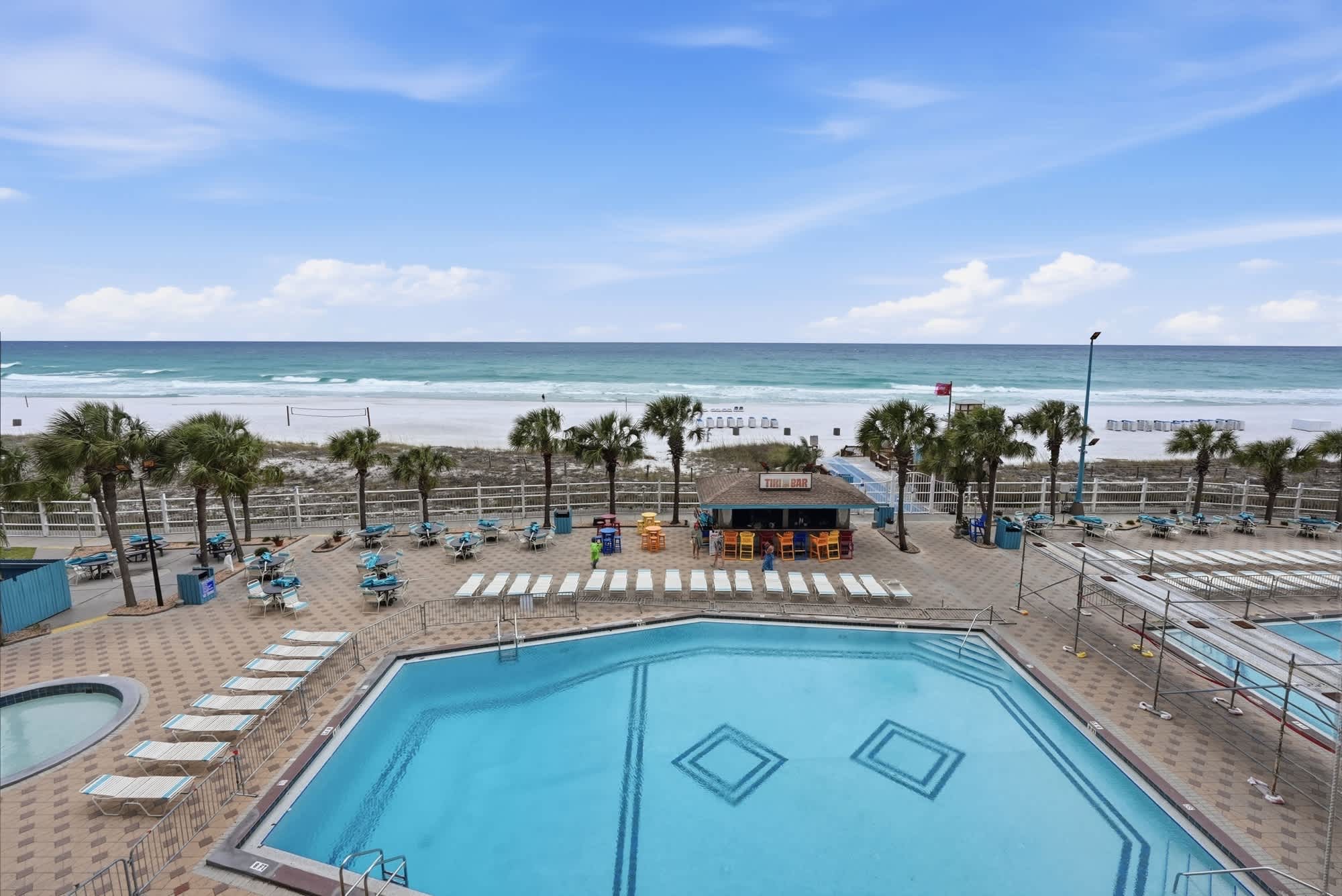 The Summit 419 – View of a pool area with lounge chairs, tiki bar, and ocean in the background.