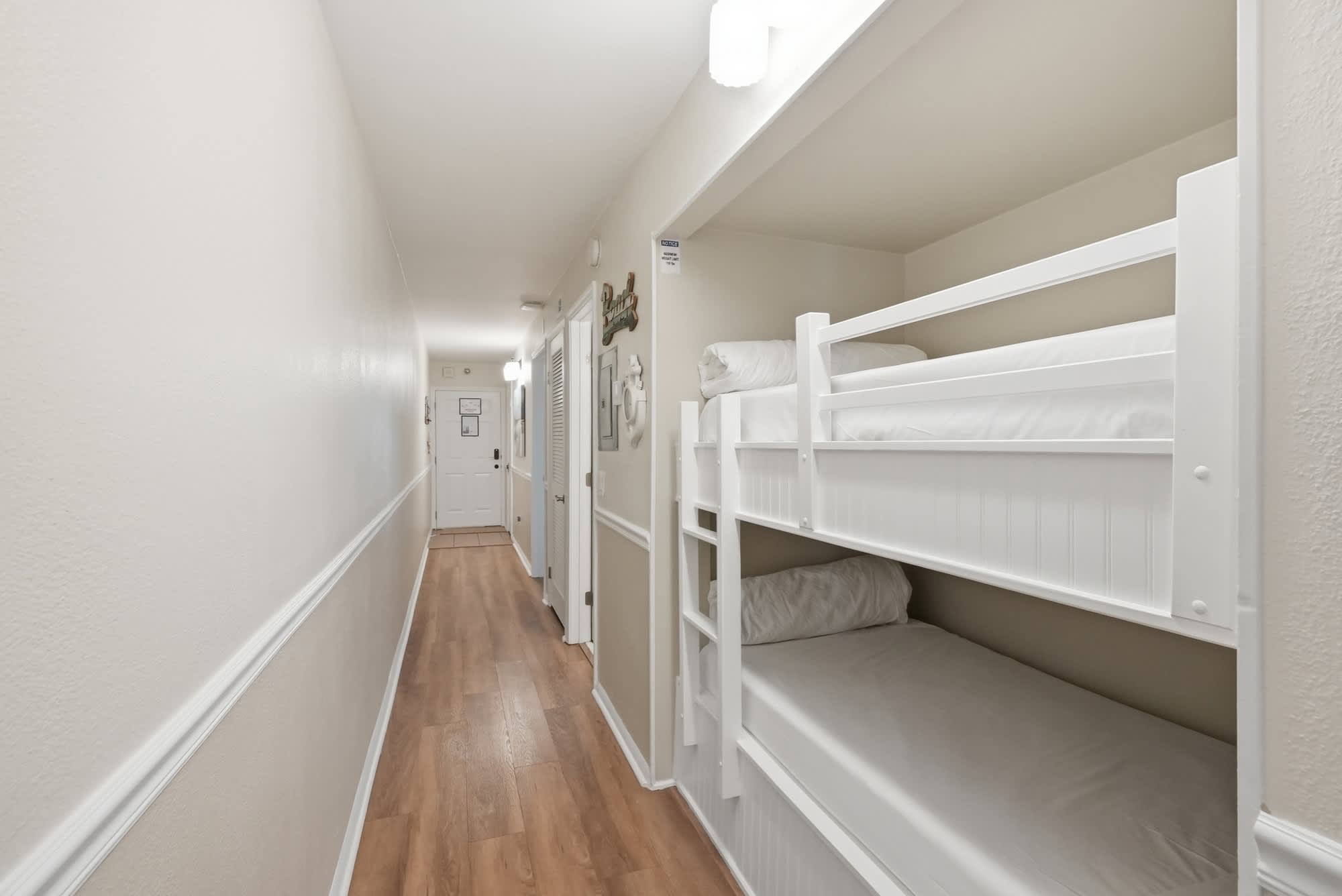 The Summit 419 – Narrow hallway with bunk beds on the right and doors on the left leading to other rooms.