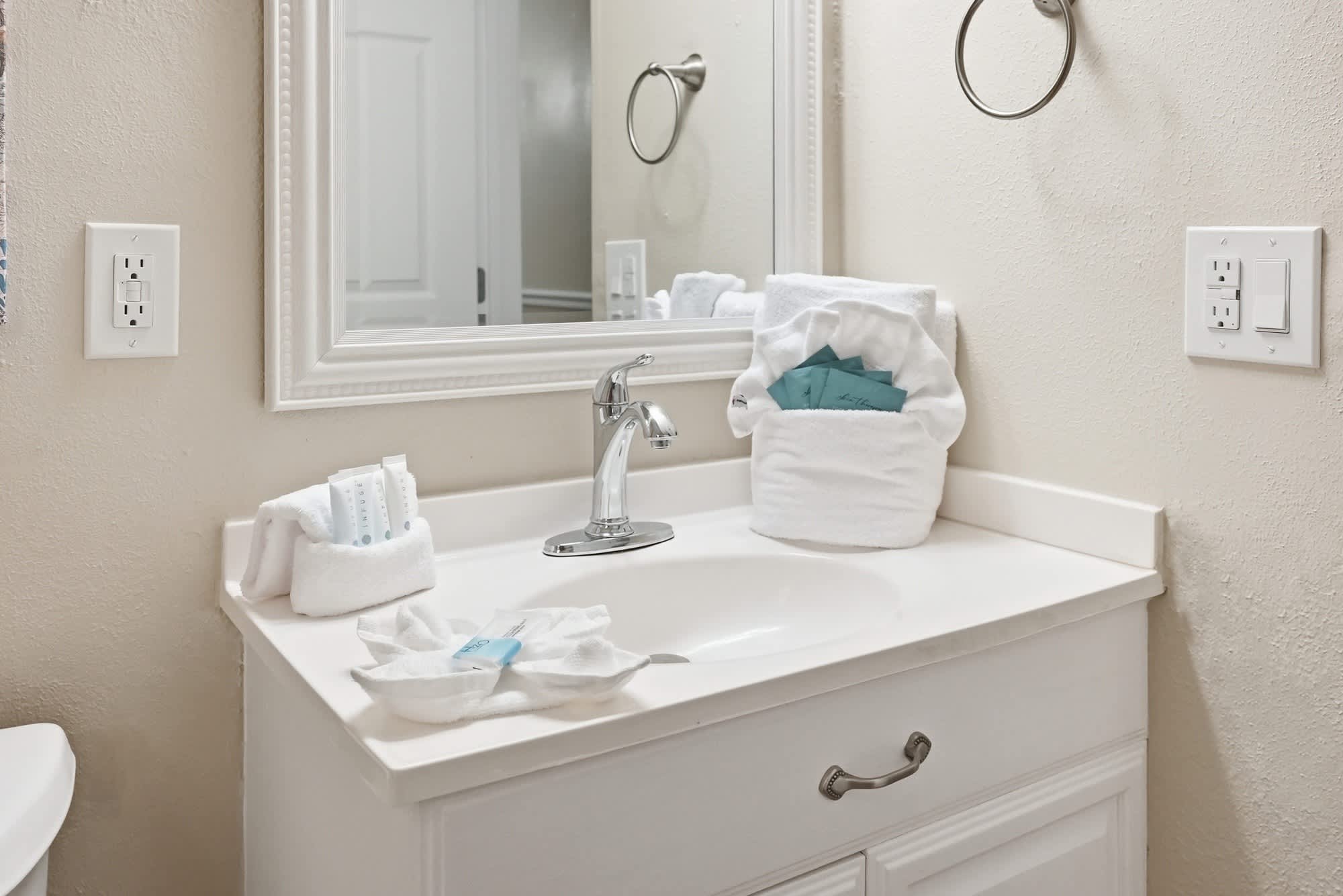 The Summit 419 – Bathroom vanity with sink, mirror, towels, and toiletries in a clean, neutral-colored space.