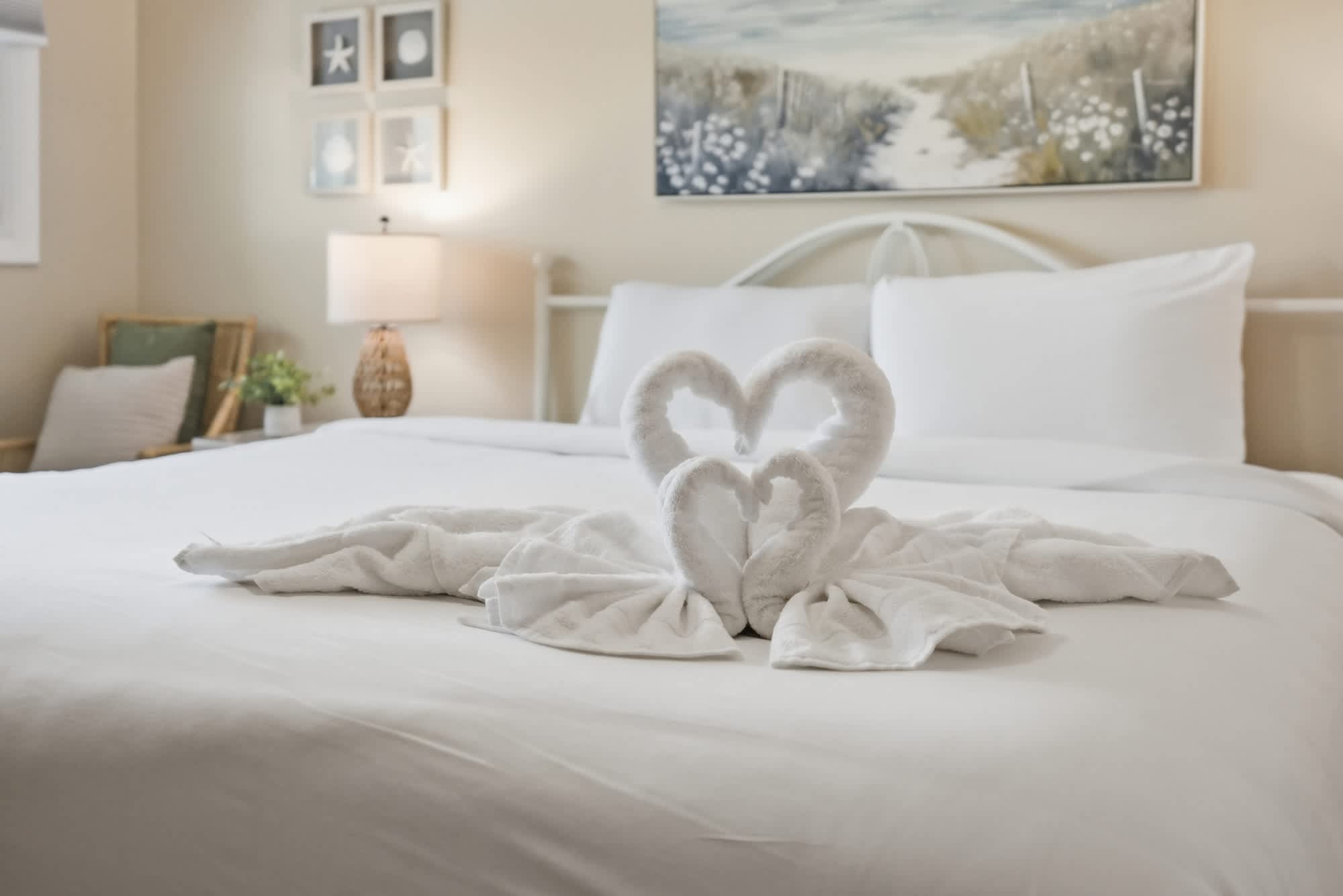 The Summit 419 – Bedroom with a white bed, heart-shaped towel arrangements, lamp, and artwork on the wall.