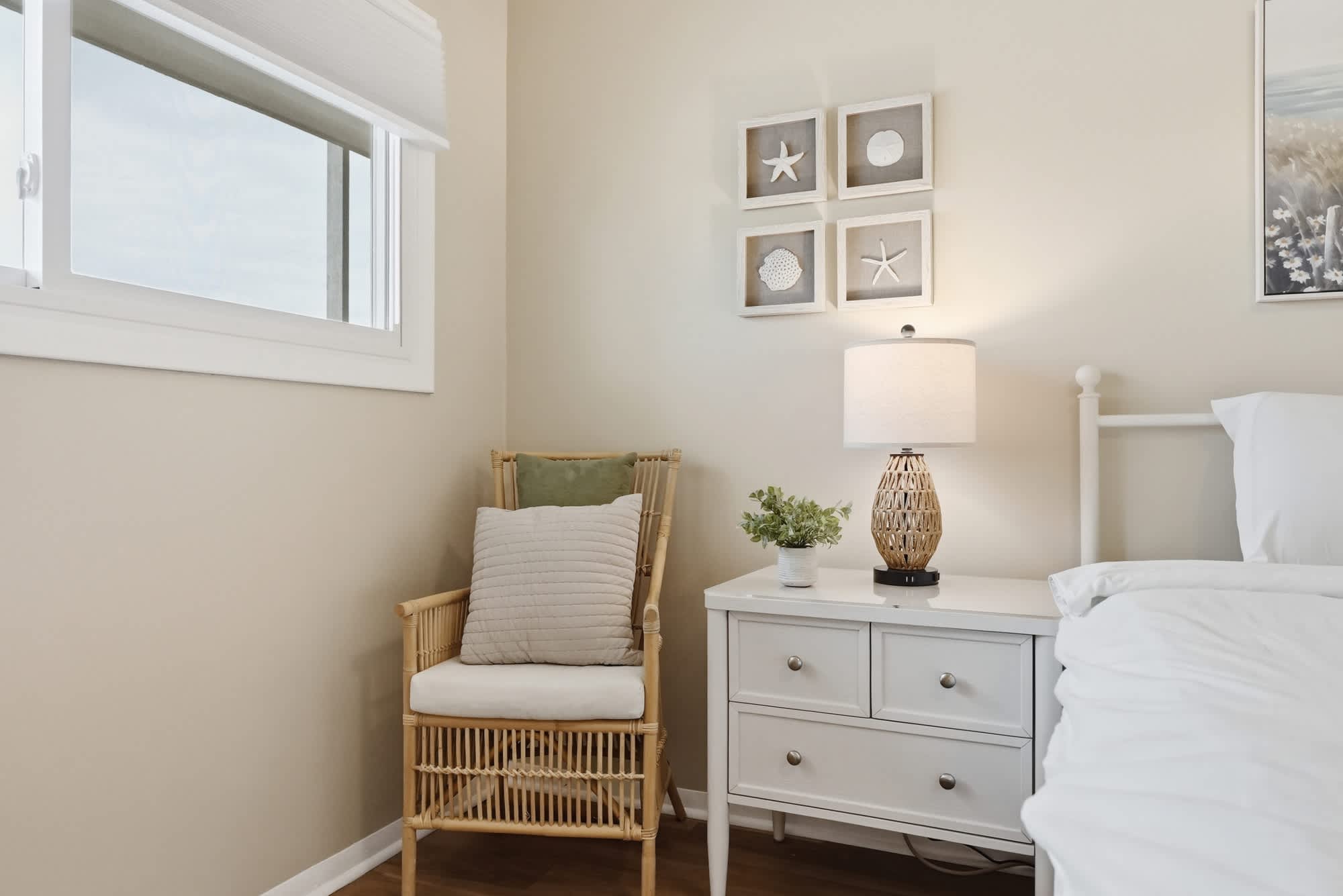 The Summit 419 – Cozy bedroom with a wicker chair, bedside table, and decorative wall art.