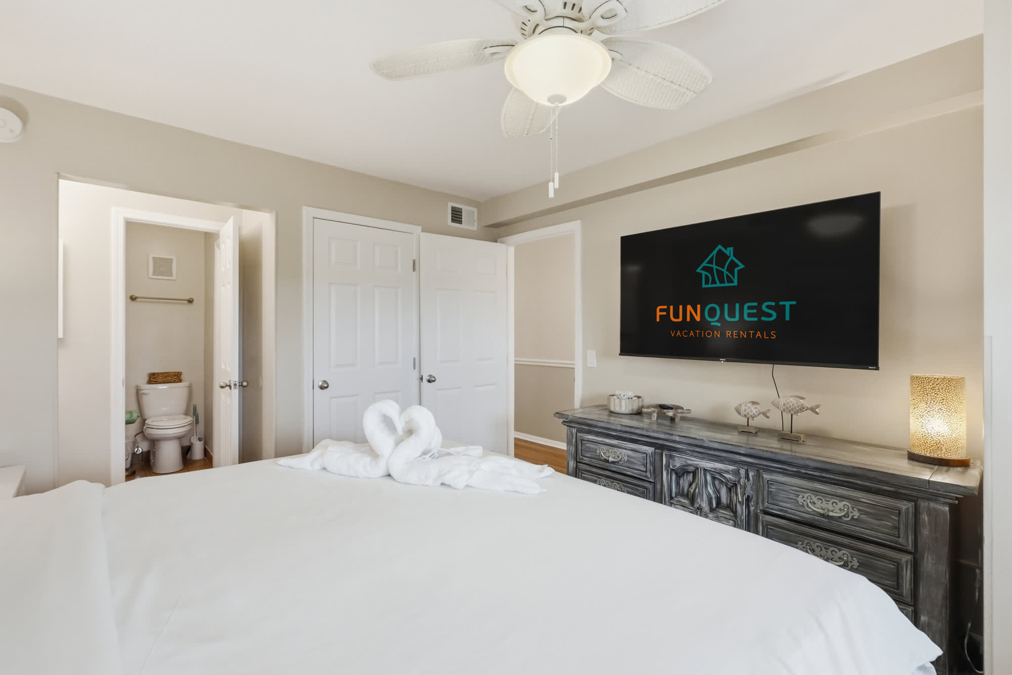 The Summit 419 – Bedroom with a large bed, TV, decorative light, and bathroom door visible in background.