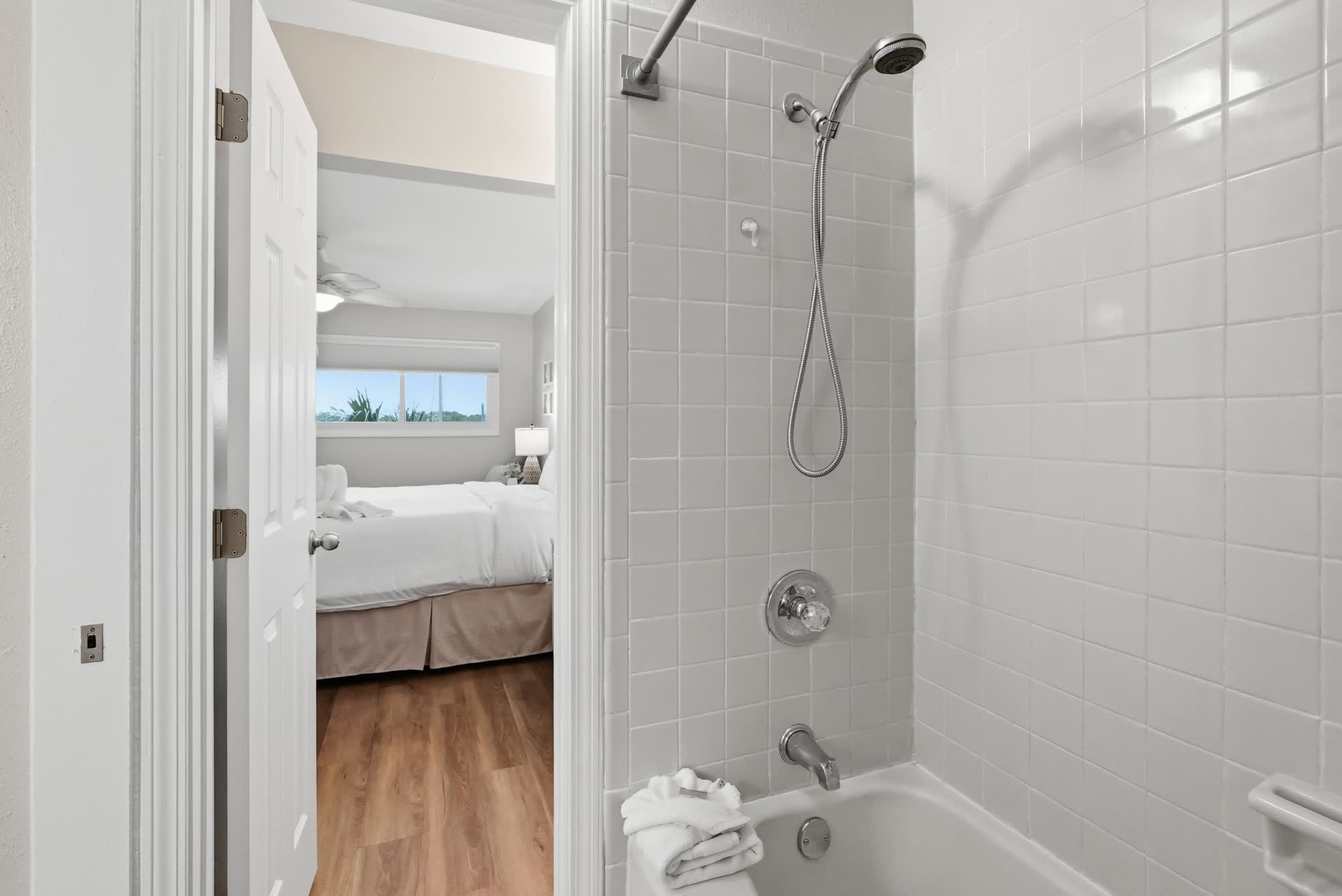 The Summit 419 – Bathroom with shower and tub, view into bedroom featuring a white bed and window.