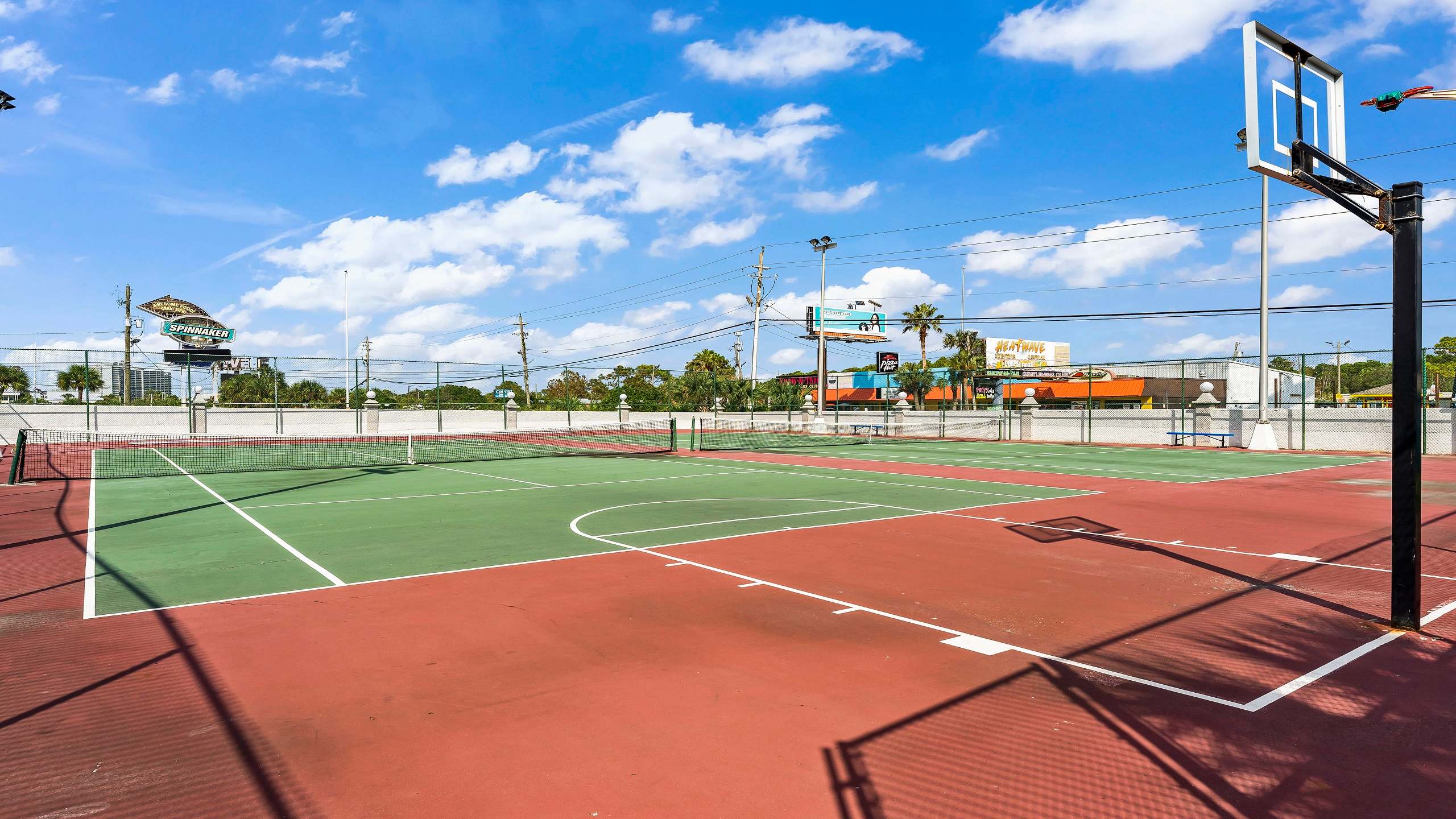 The Summit 419 – Outdoor sports court featuring tennis nets and a basketball hoop, surrounded by palm trees and blue skies.
