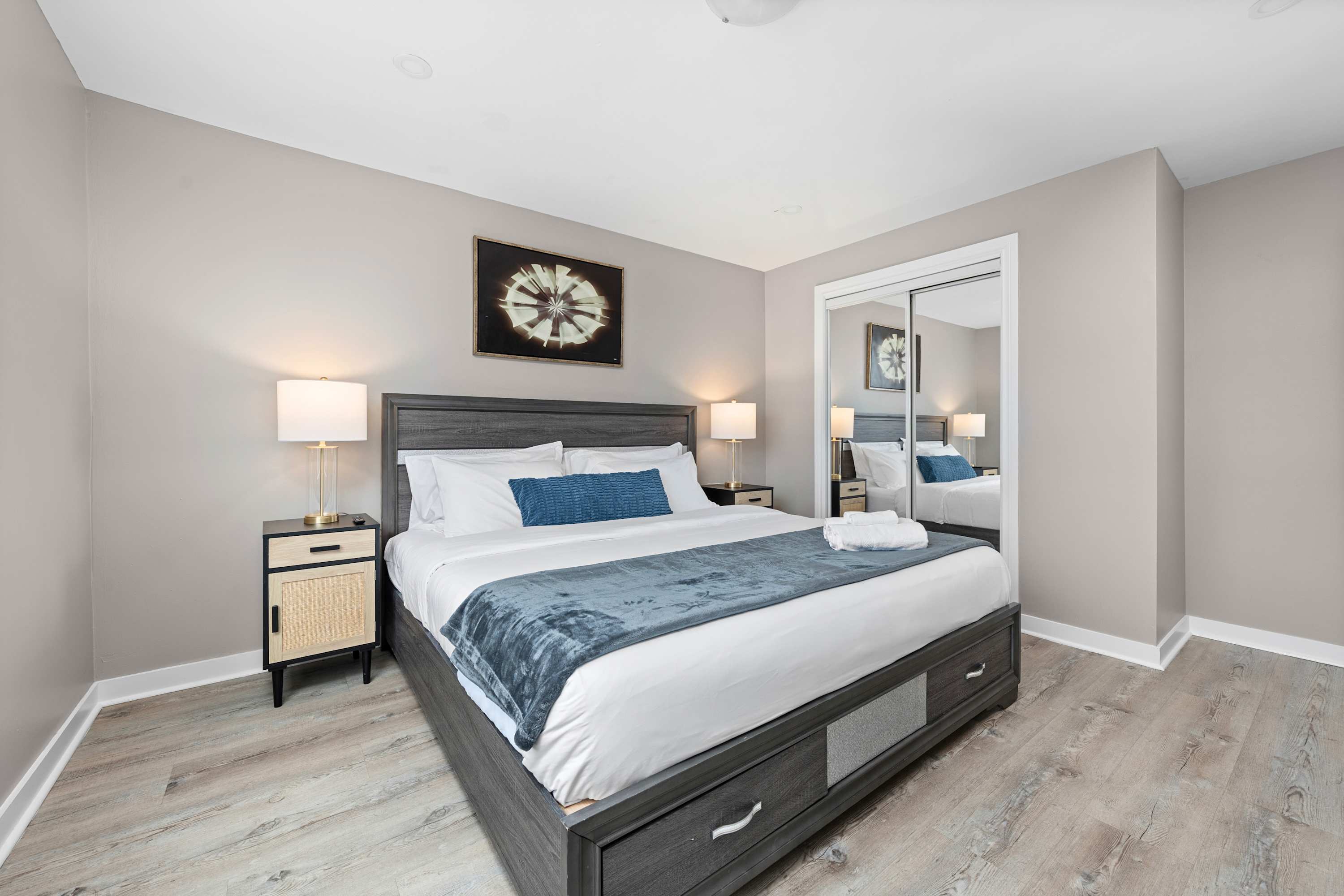 Master bedroom with a king bed, warm bedside lamps, and a sleek mirrored cabinet.