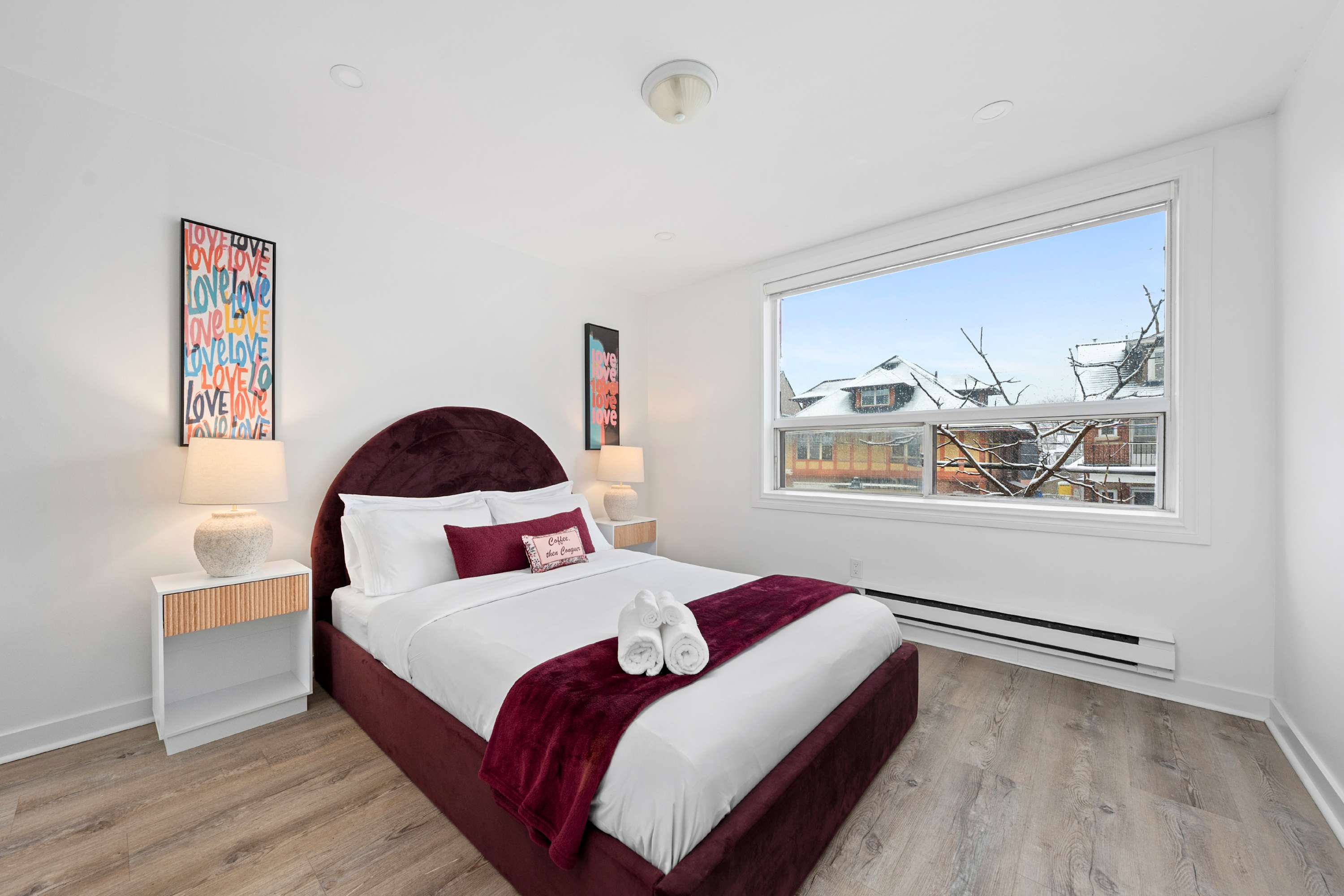Queen bedroom with red silk linens, fresh towels, and cozy bedside lighting.