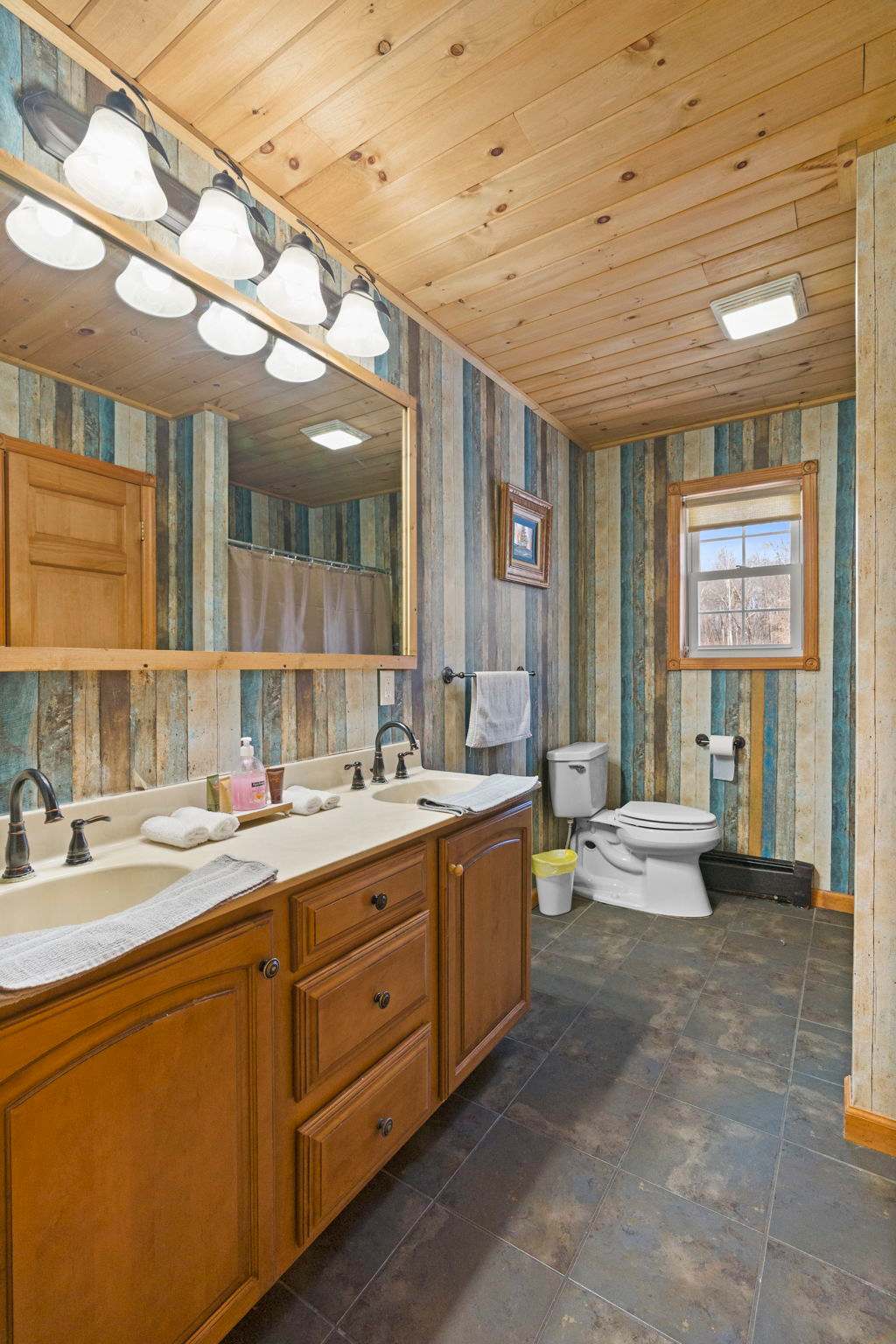 Double vanity bathroom with reclaimed wood walls and a skylight above
