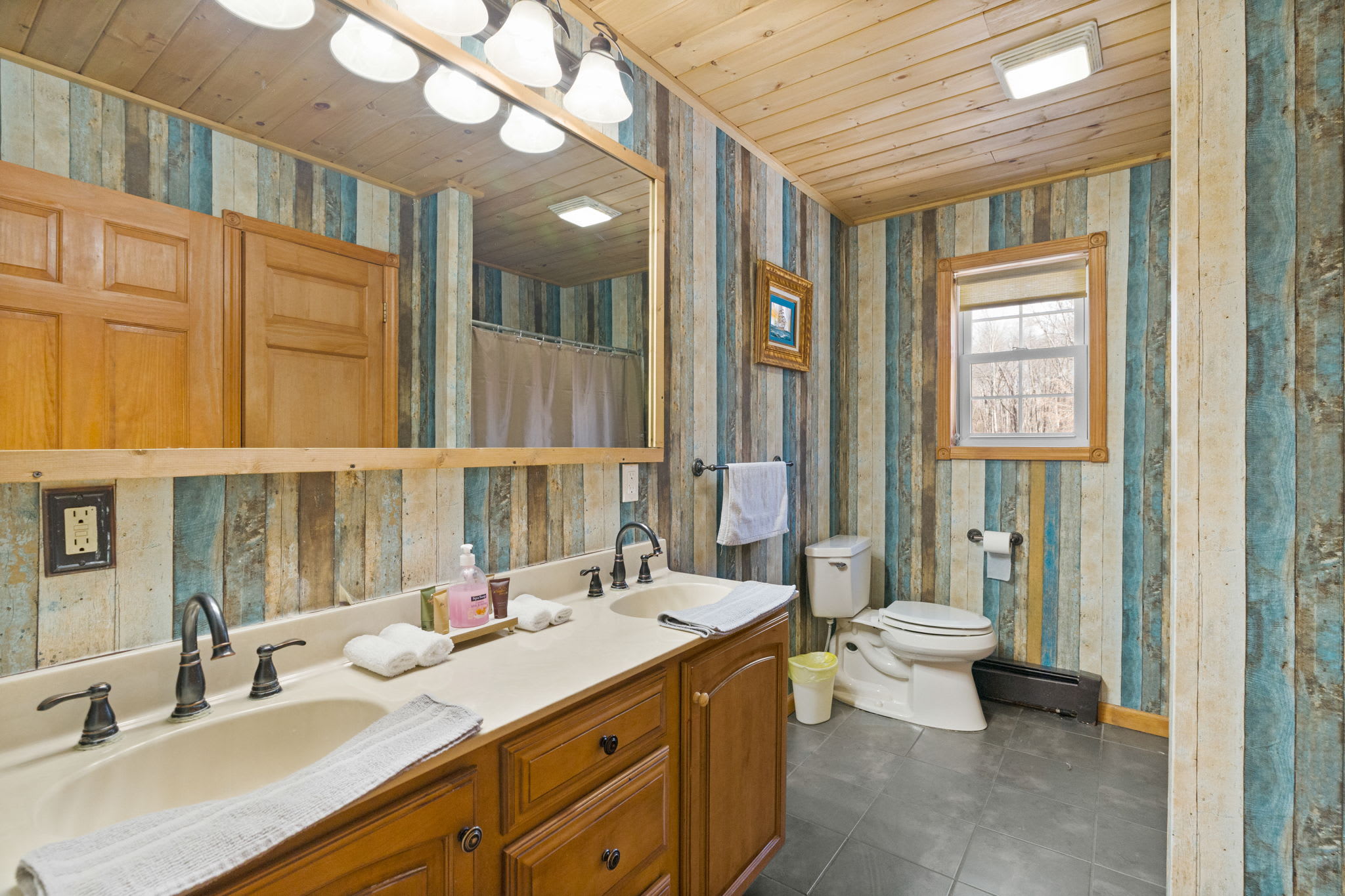 Full bathroom with shower, double sinks, and a skylight for natural glow