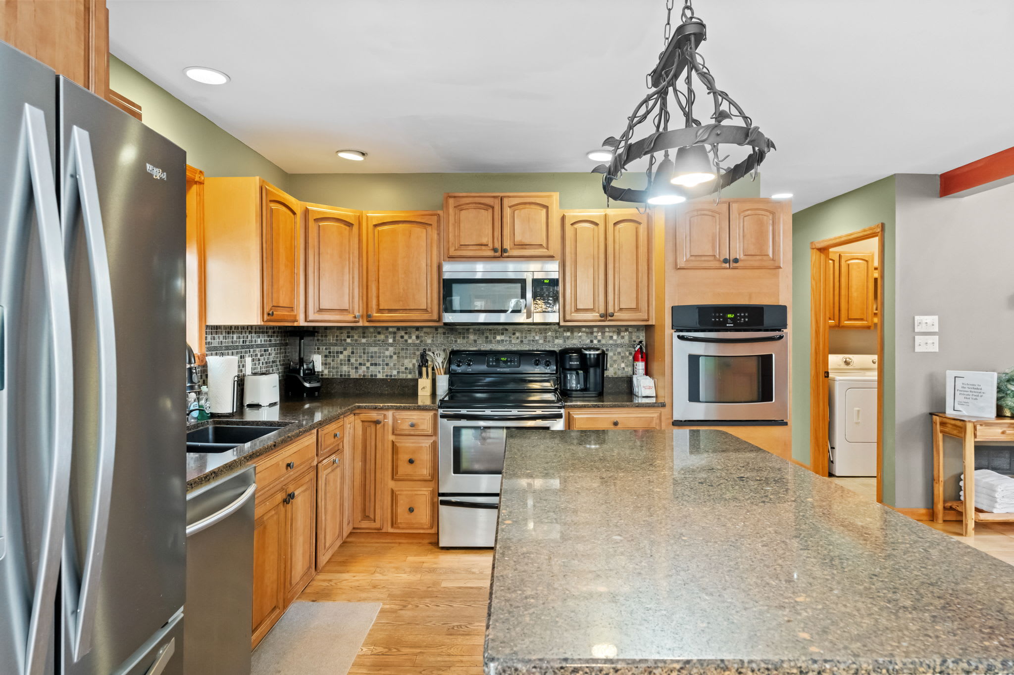 Oak cabinets, double wall ovens, and a wrought iron chandelier above the island