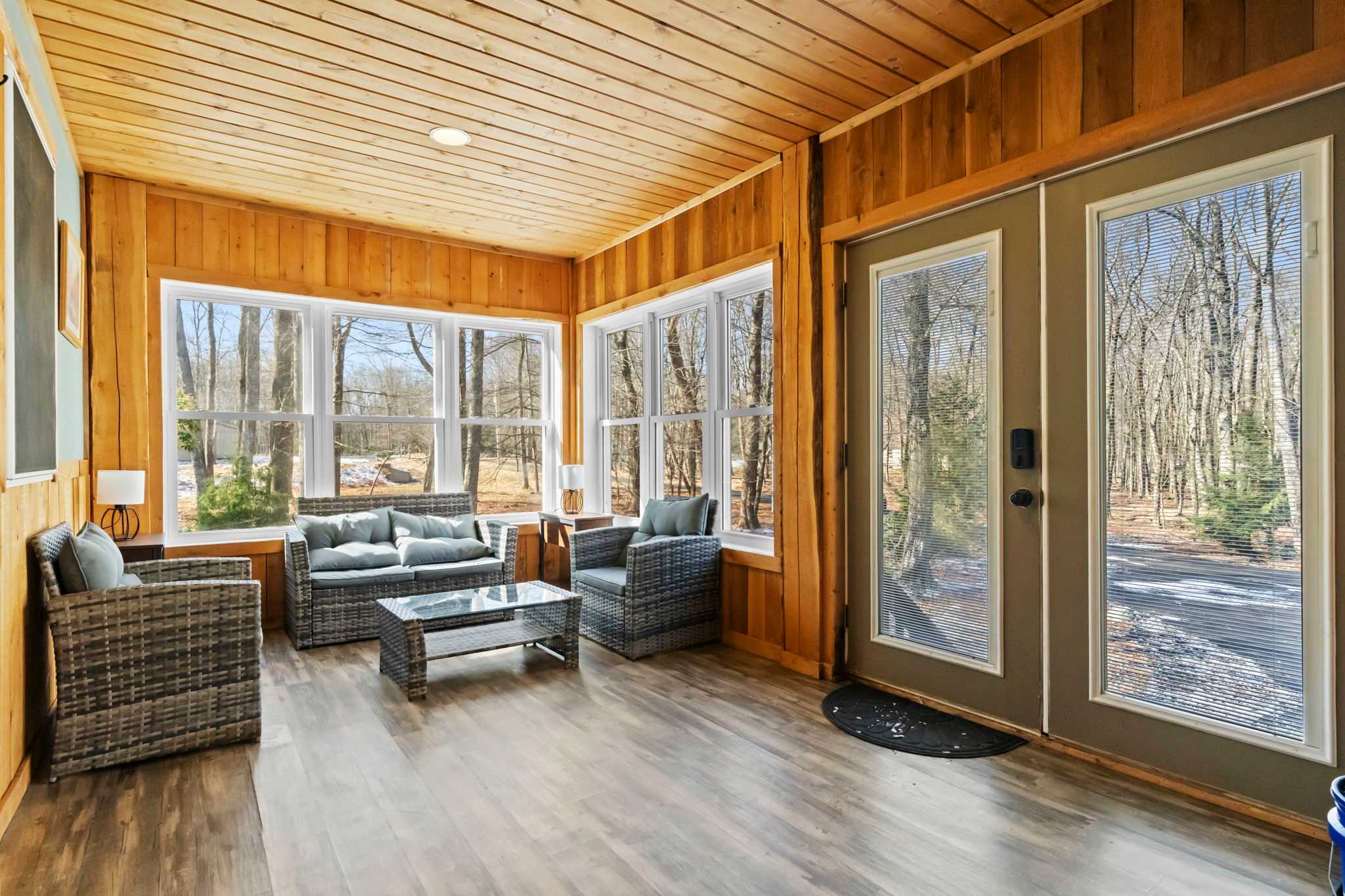 A bright sitting room with woodland views through floor-to-ceiling windows