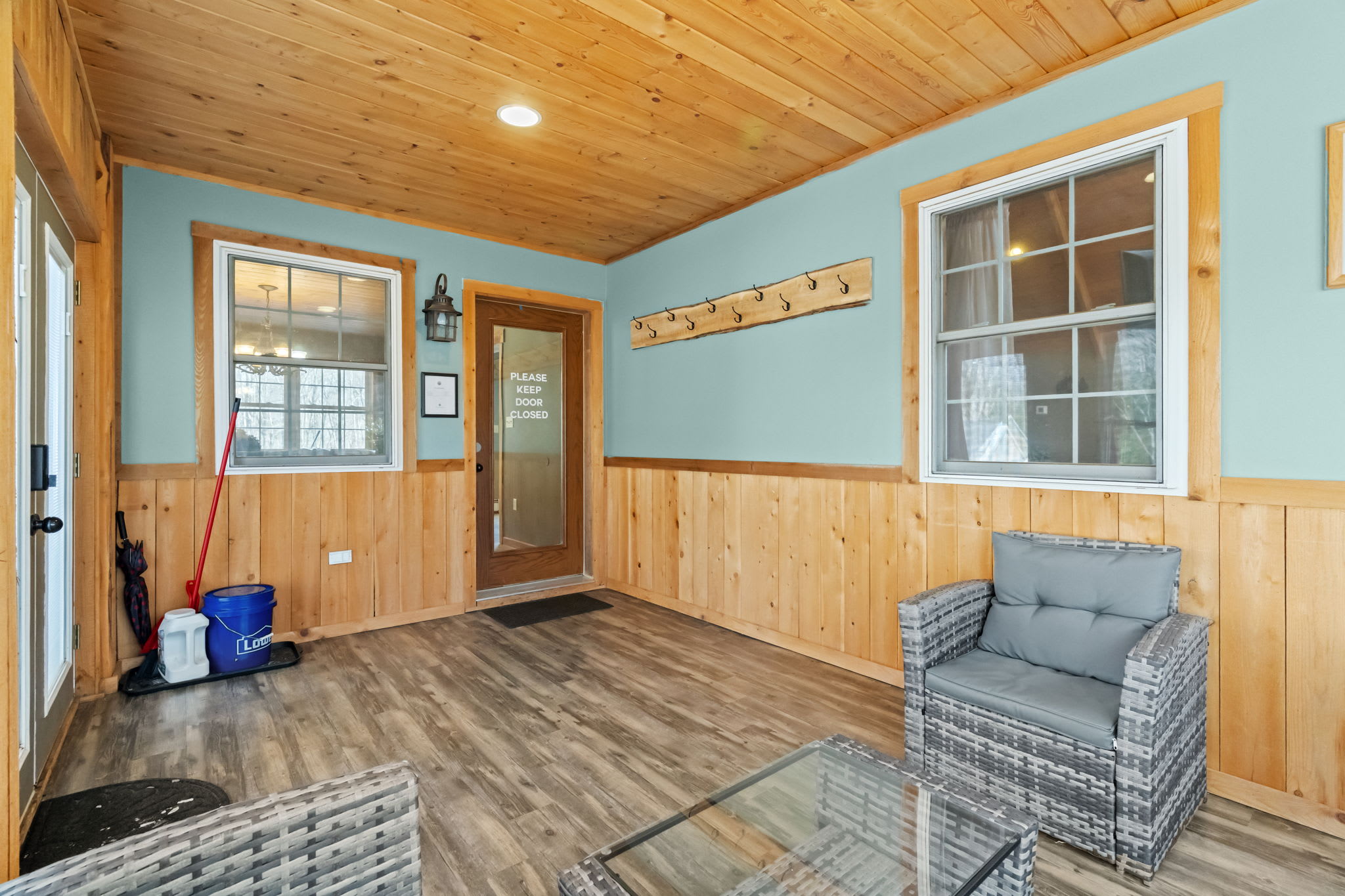 Step through the charming entryway with warm wood paneling and a pop of blue