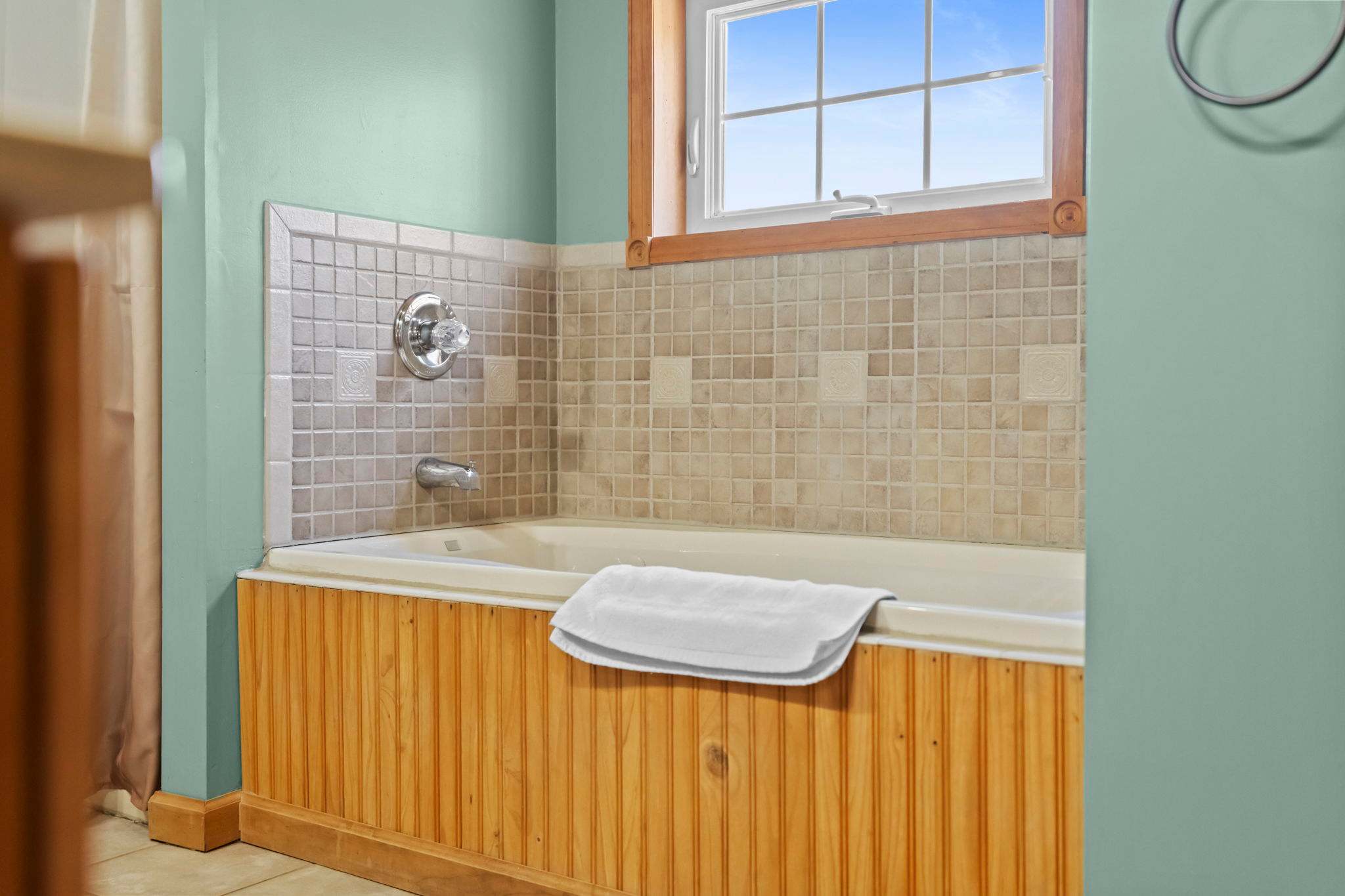 Upper bathroom with a soaking tub, wood ceiling, and natural skylight