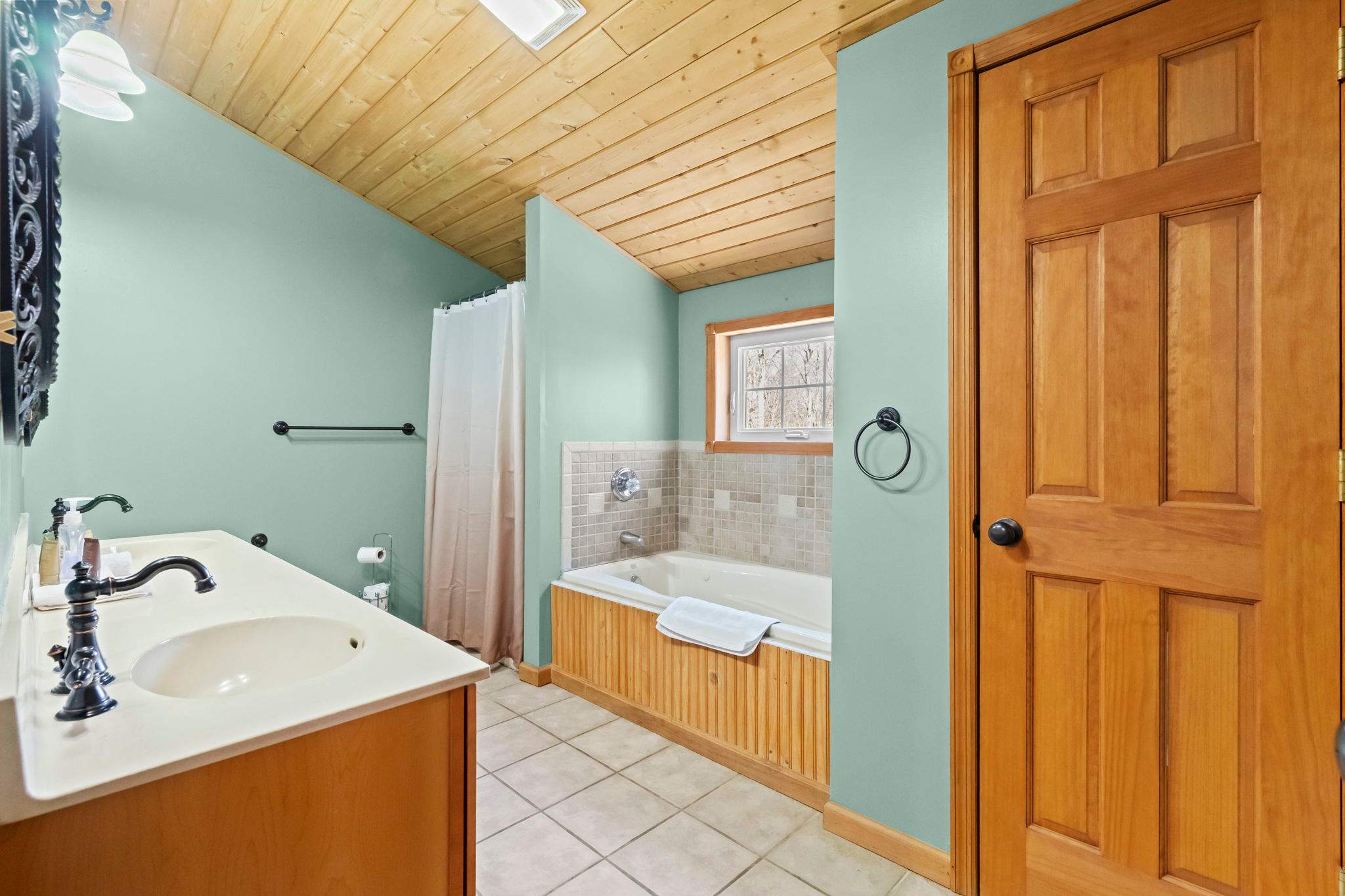 Cozy wood-paneled bathroom with a shower-tub combo and warm cabin feel