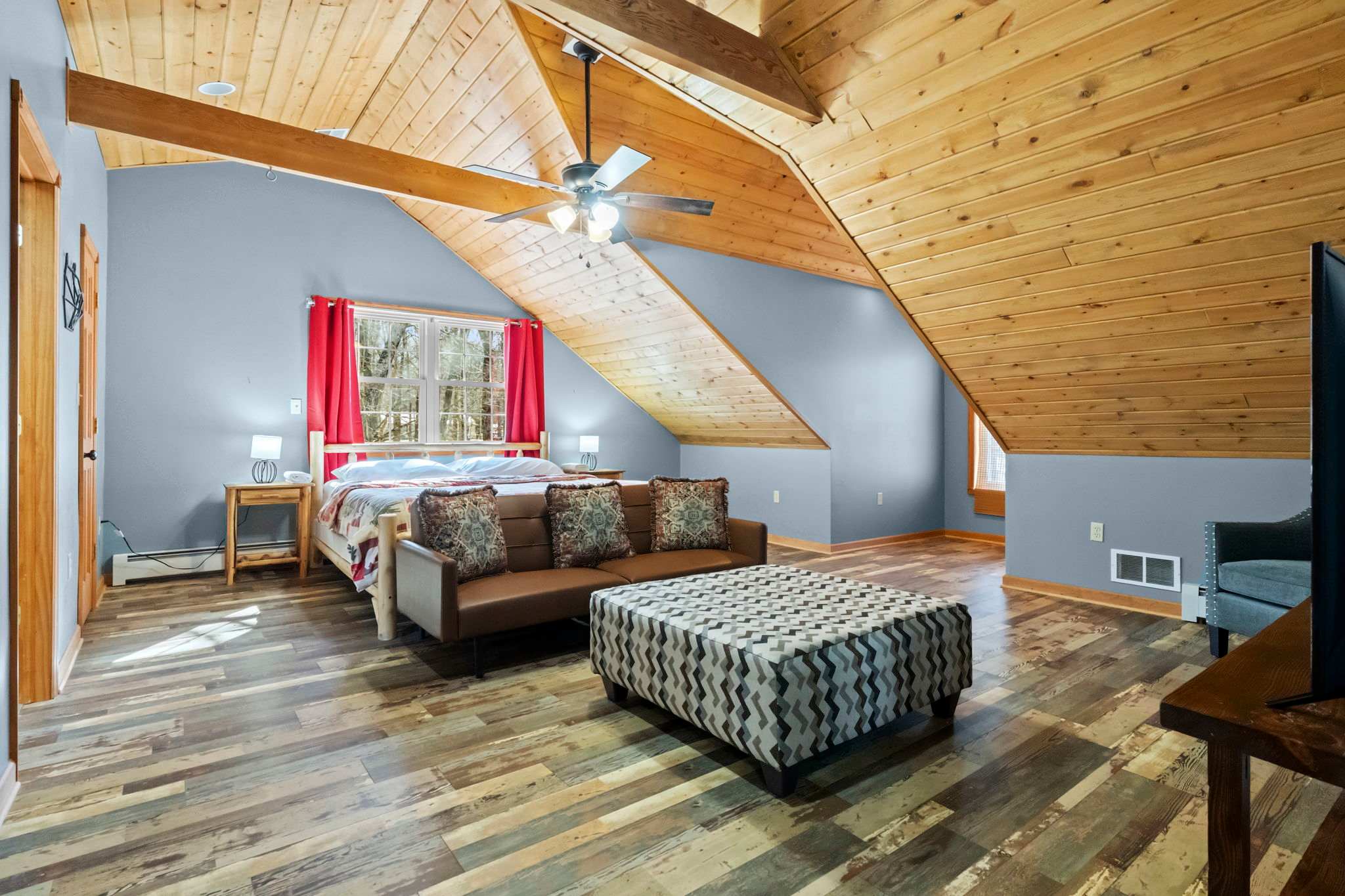 Charming bedroom tucked under vaulted wood ceilings with cozy patterned bedding