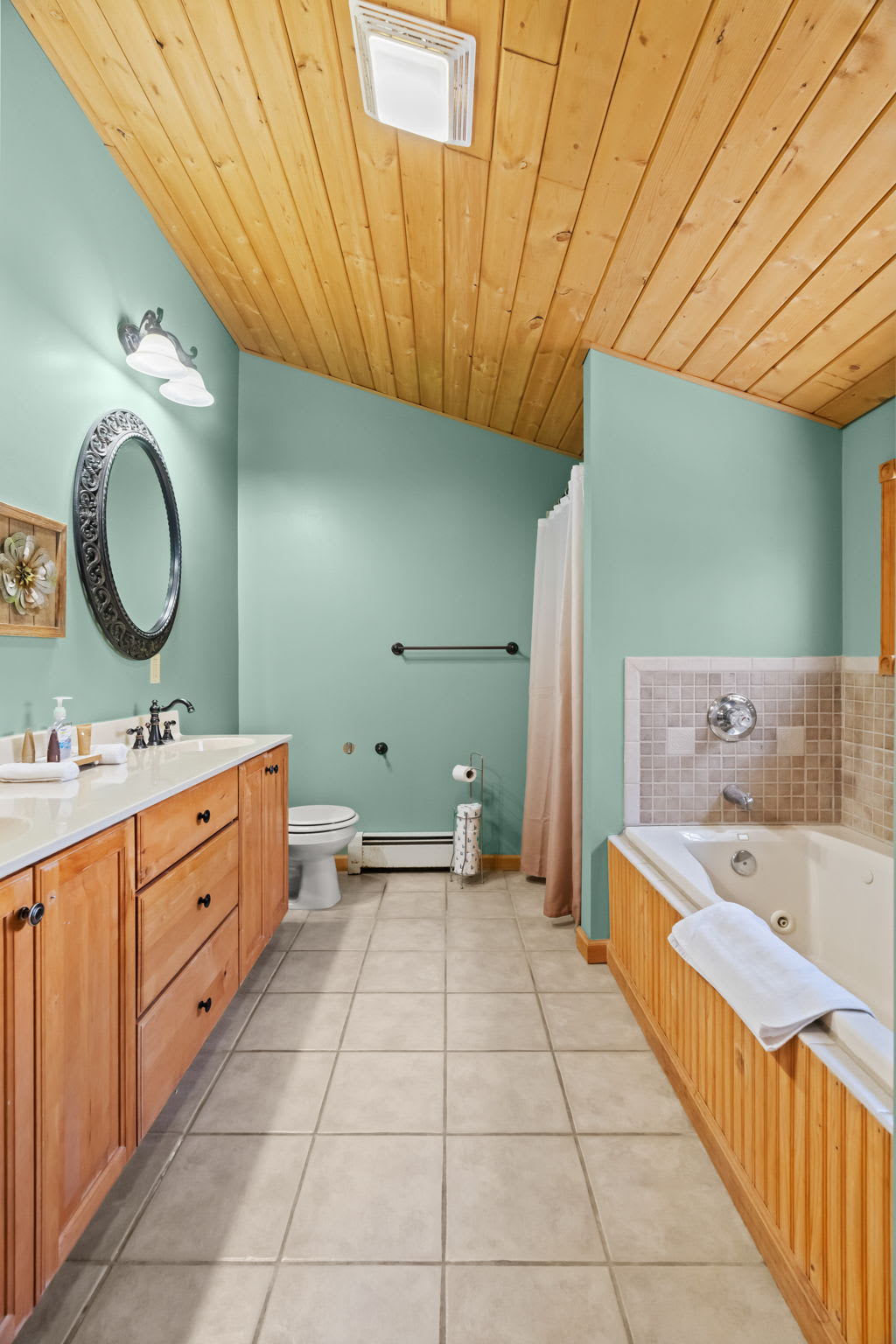 Bright teal bathroom with tile floors and a vaulted wood ceiling overhead
