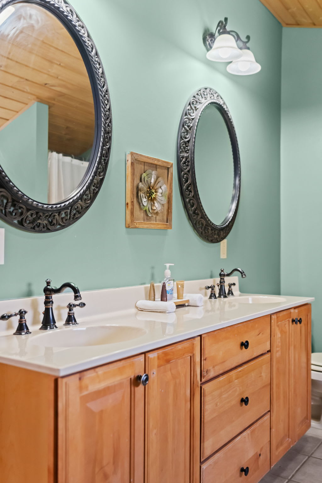 Double vanity bathroom with teal walls and a warm wooden countertop