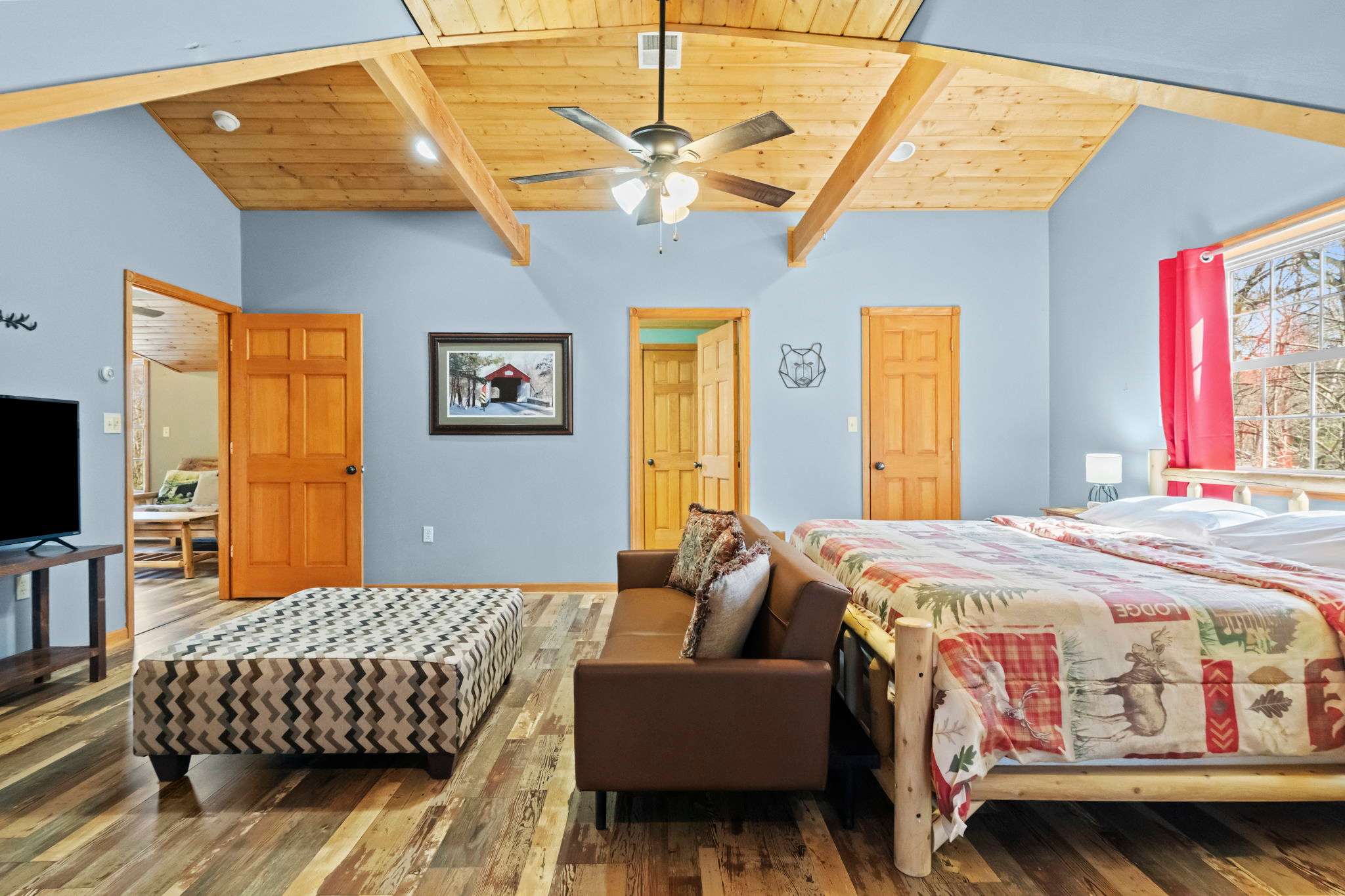Colorful bedroom retreat with teal walls, red drapes, and a soaring wood ceiling