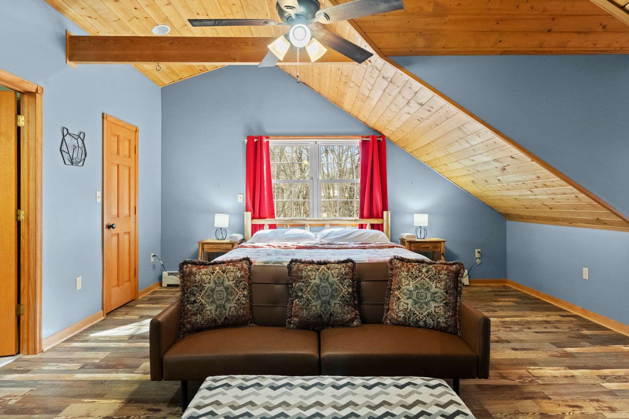 Bold red curtains and vaulted wood ceilings give this bedroom a cabin lodge feel