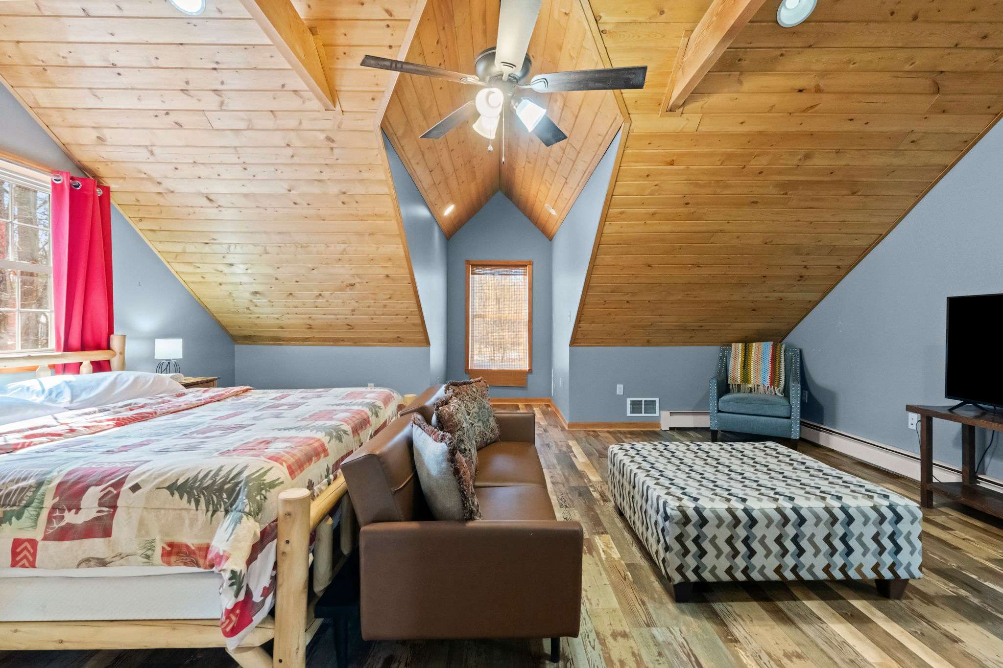 Spacious upper bedroom with curtains and a tall vaulted wood ceiling