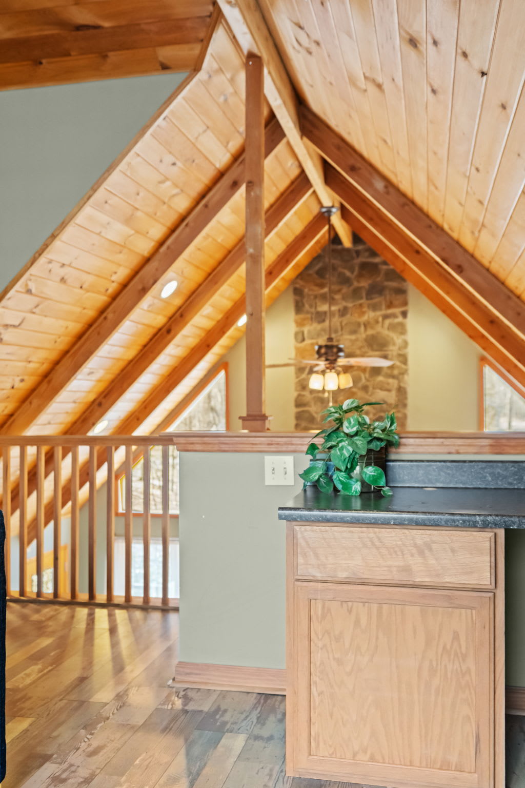 Look over the railing from the loft to the living room and stone fireplace below