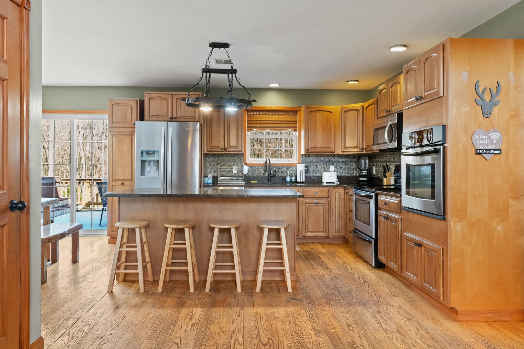Another view of the kitchen with gleaming hardwood floors and a ceiling fan