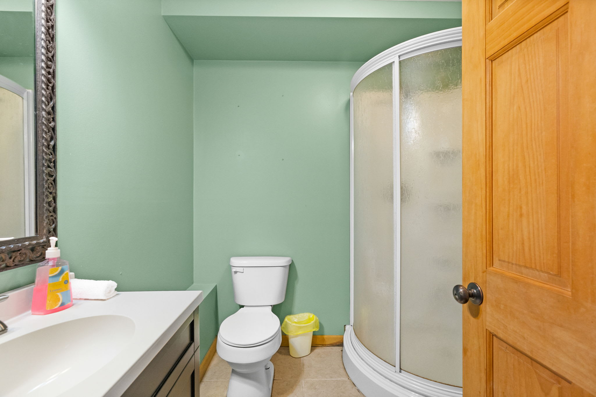 Compact lower-level bathroom with wood paneling and a clean, cozy feel