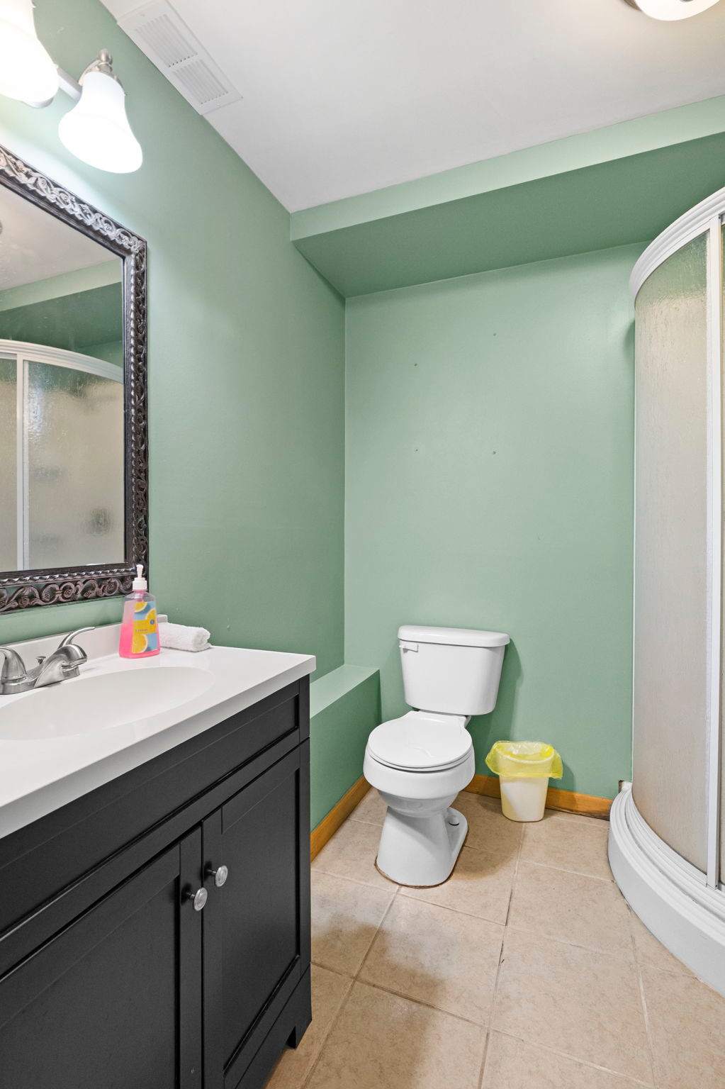 Lower-level bathroom with a glass shower and fresh green walls