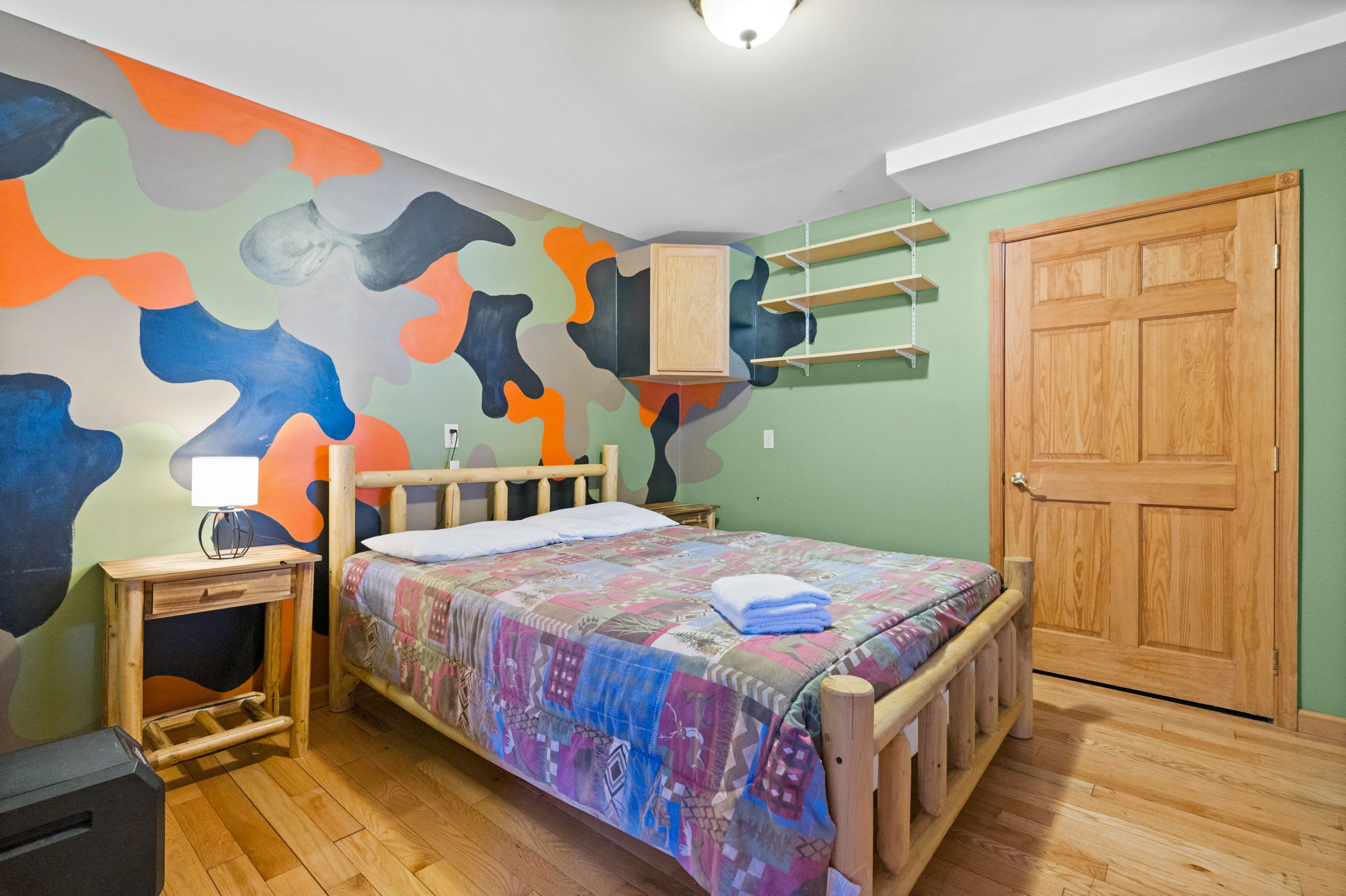 Bright lower-level bedroom with green walls and a colorful bedspread for sweet dreams