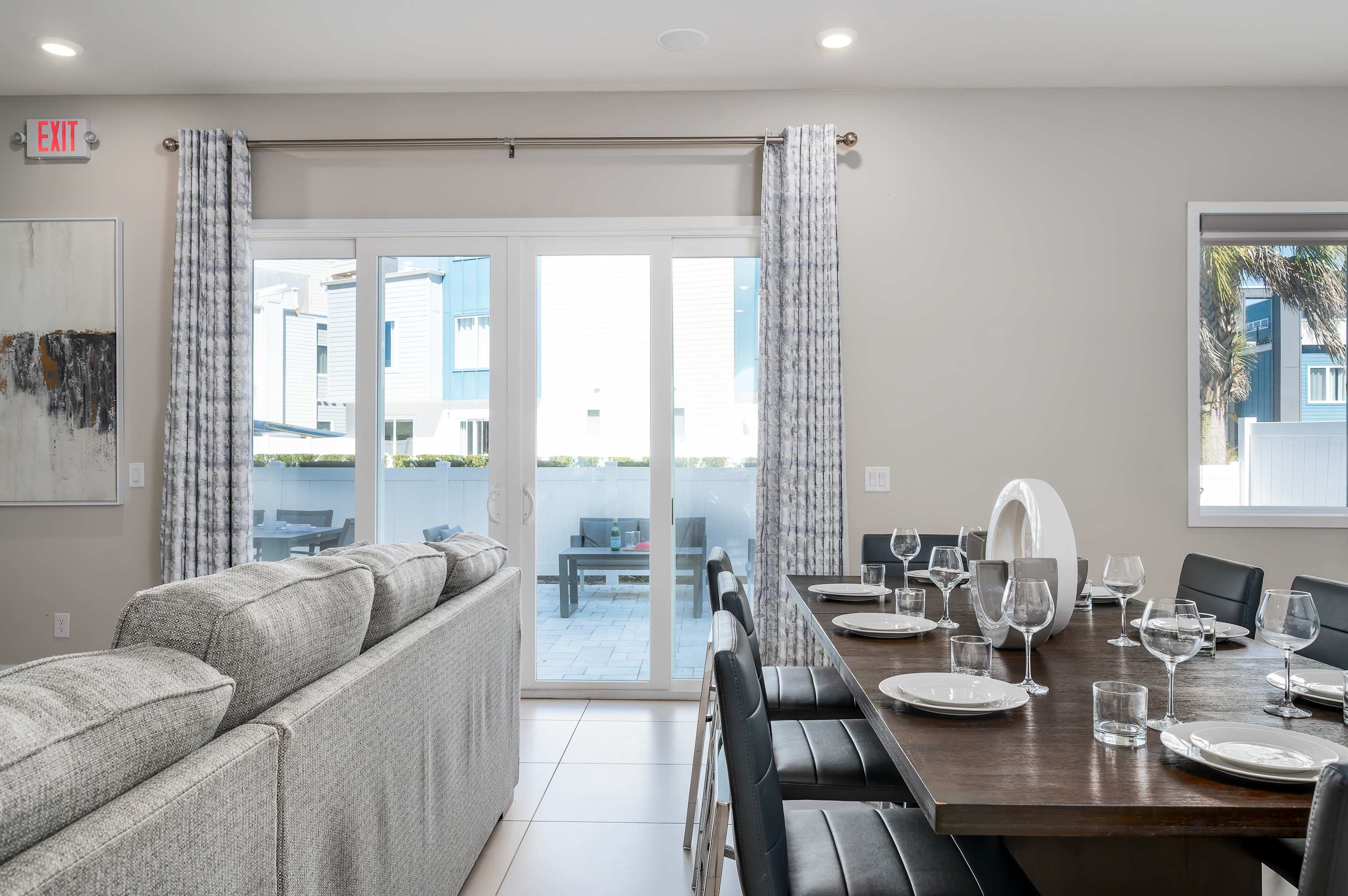 Modern dining area with seating for eight and a view of the outdoor patio through sliding glass doors.