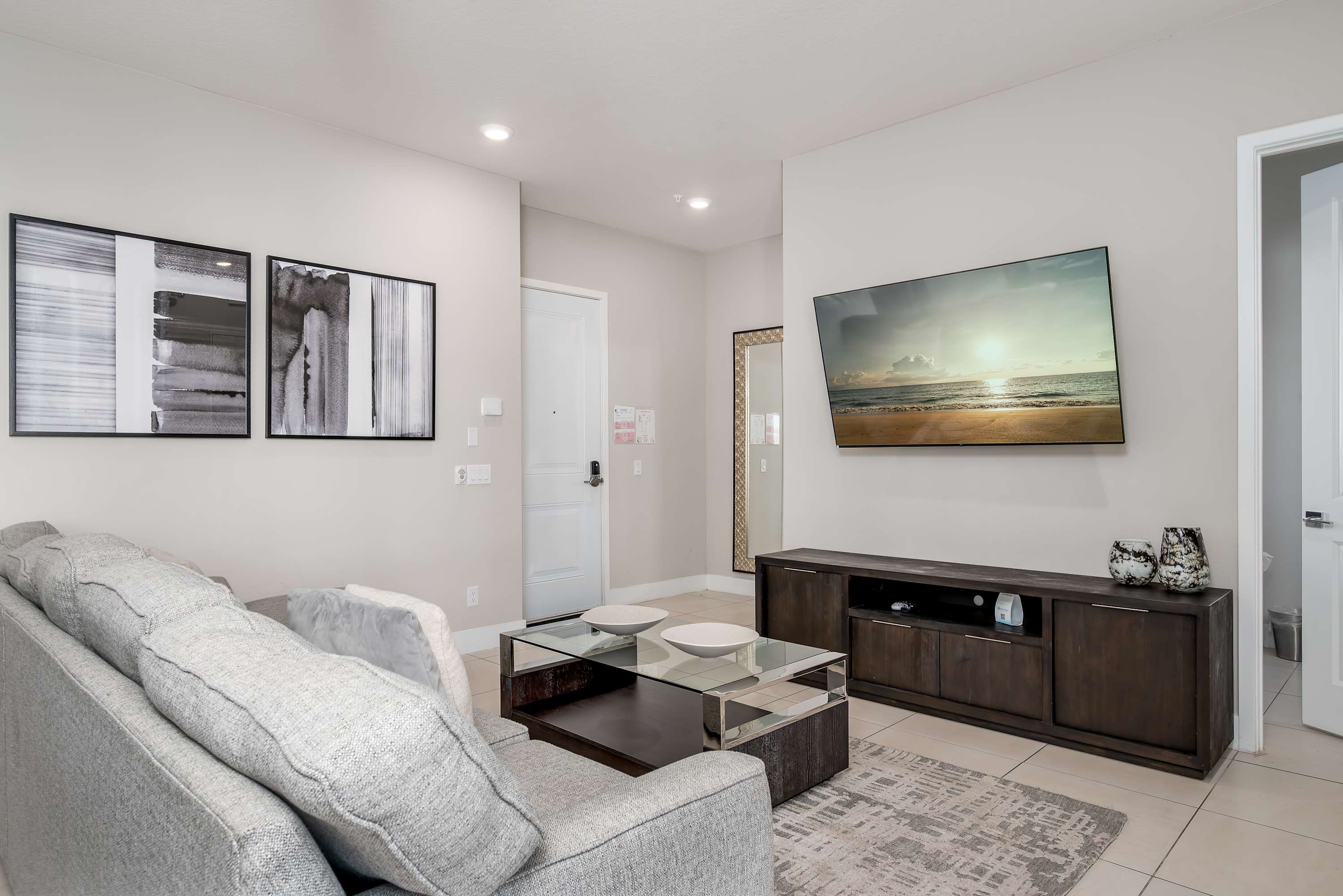 Modern living room with a large wall-mounted television and abstract artwork.