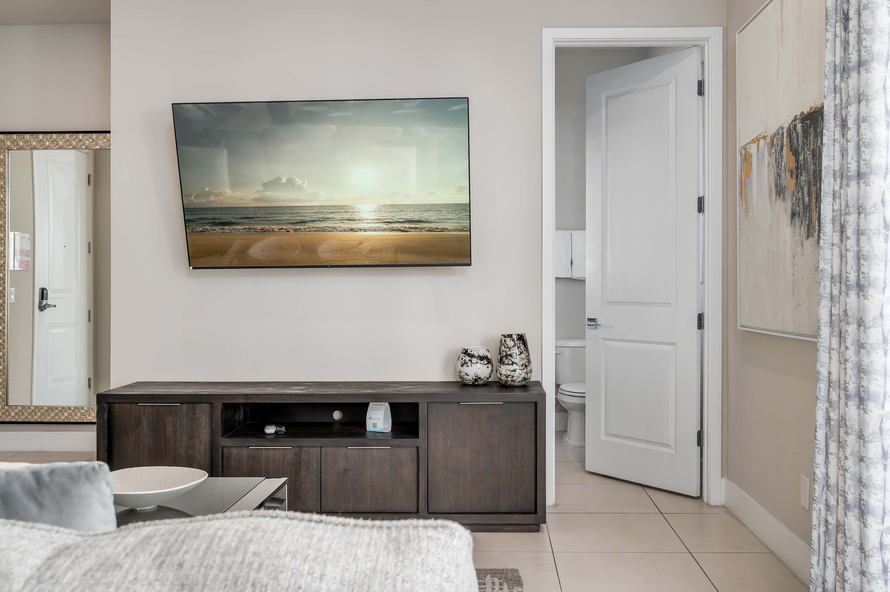 Modern living area with a wall-mounted television and decorative vases.