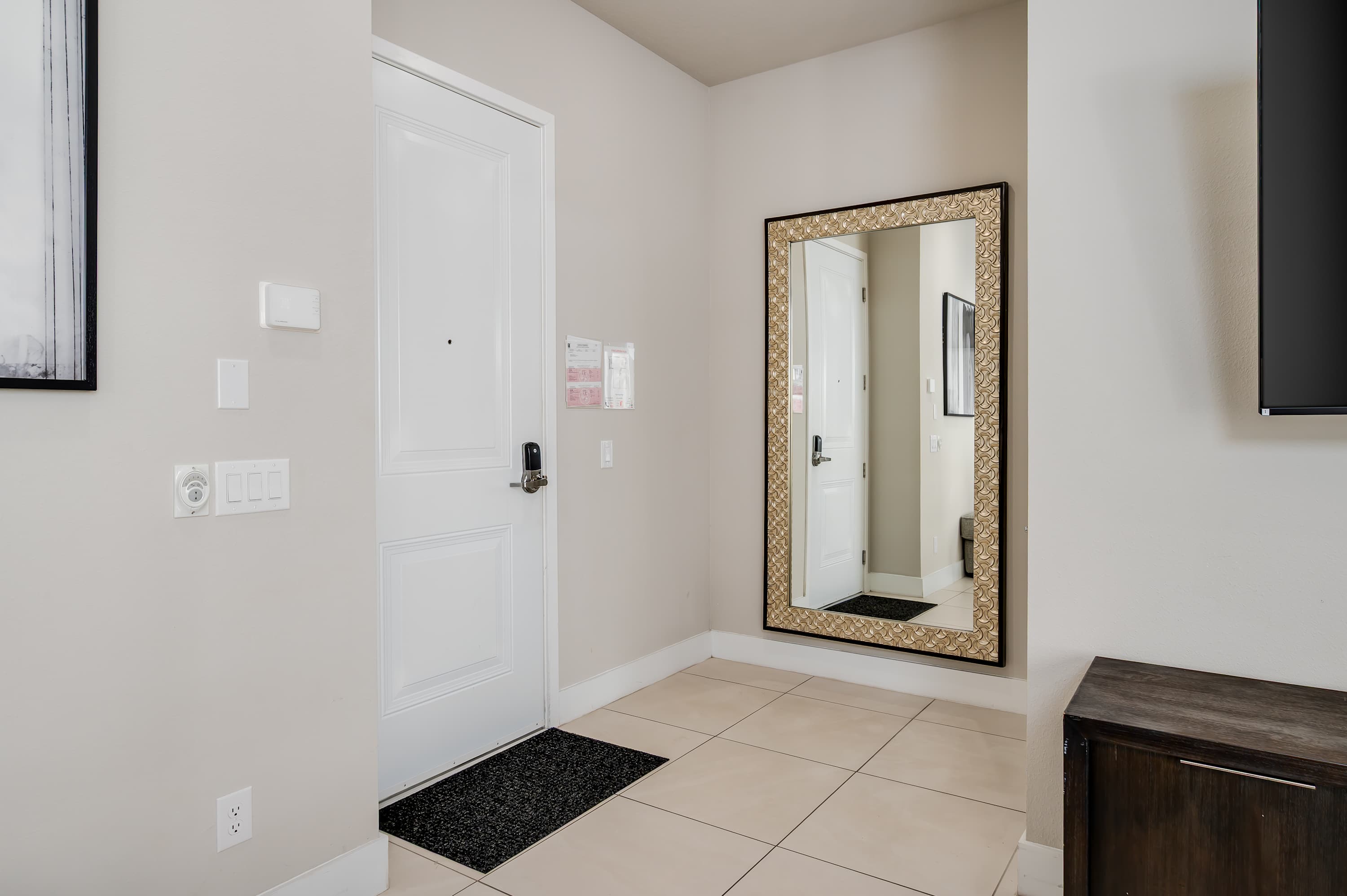 Entryway with a decorative framed mirror and tiled flooring