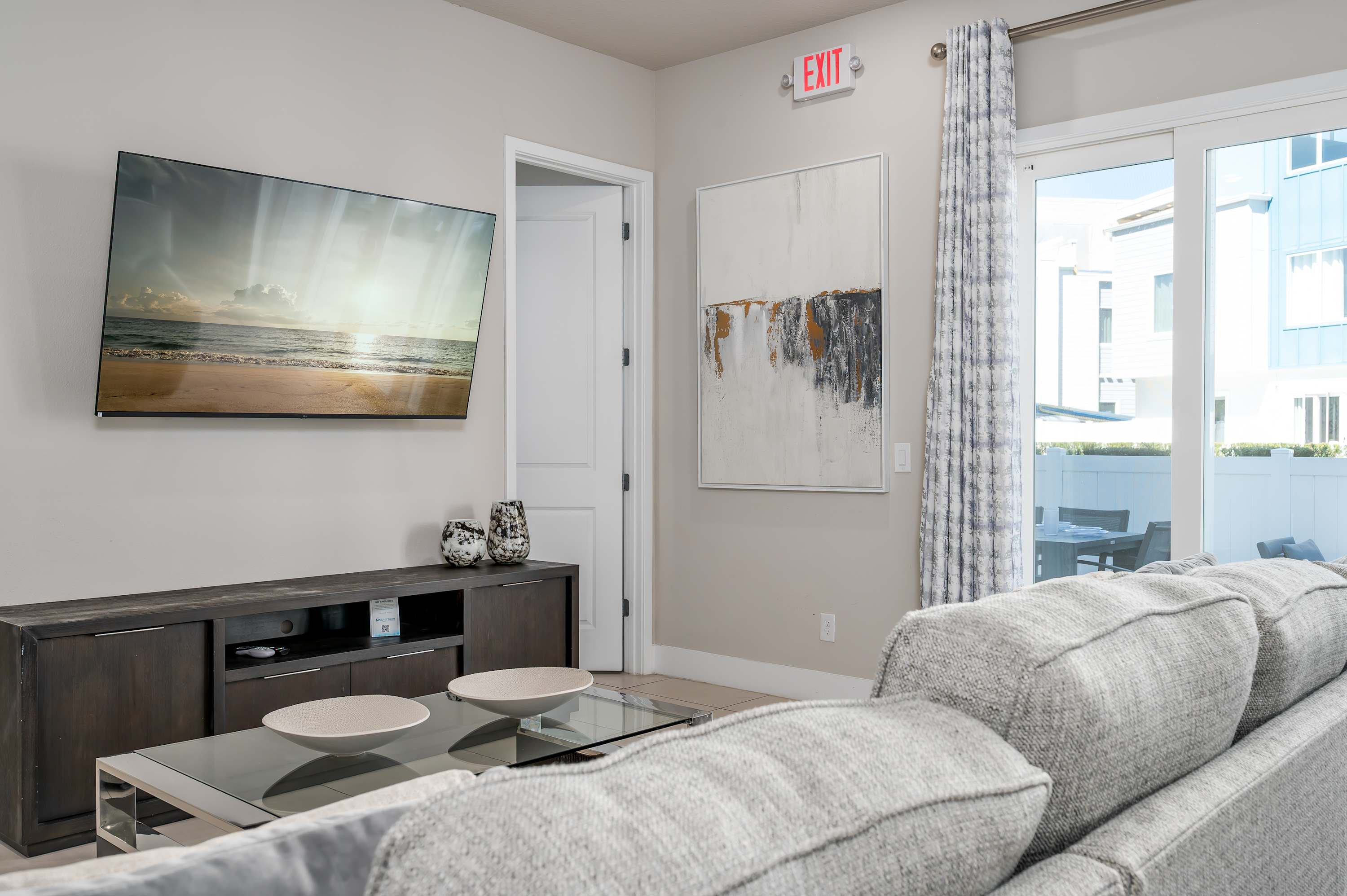 Modern living room with a large flat-screen tv and sliding glass doors leading to an outdoor patio.