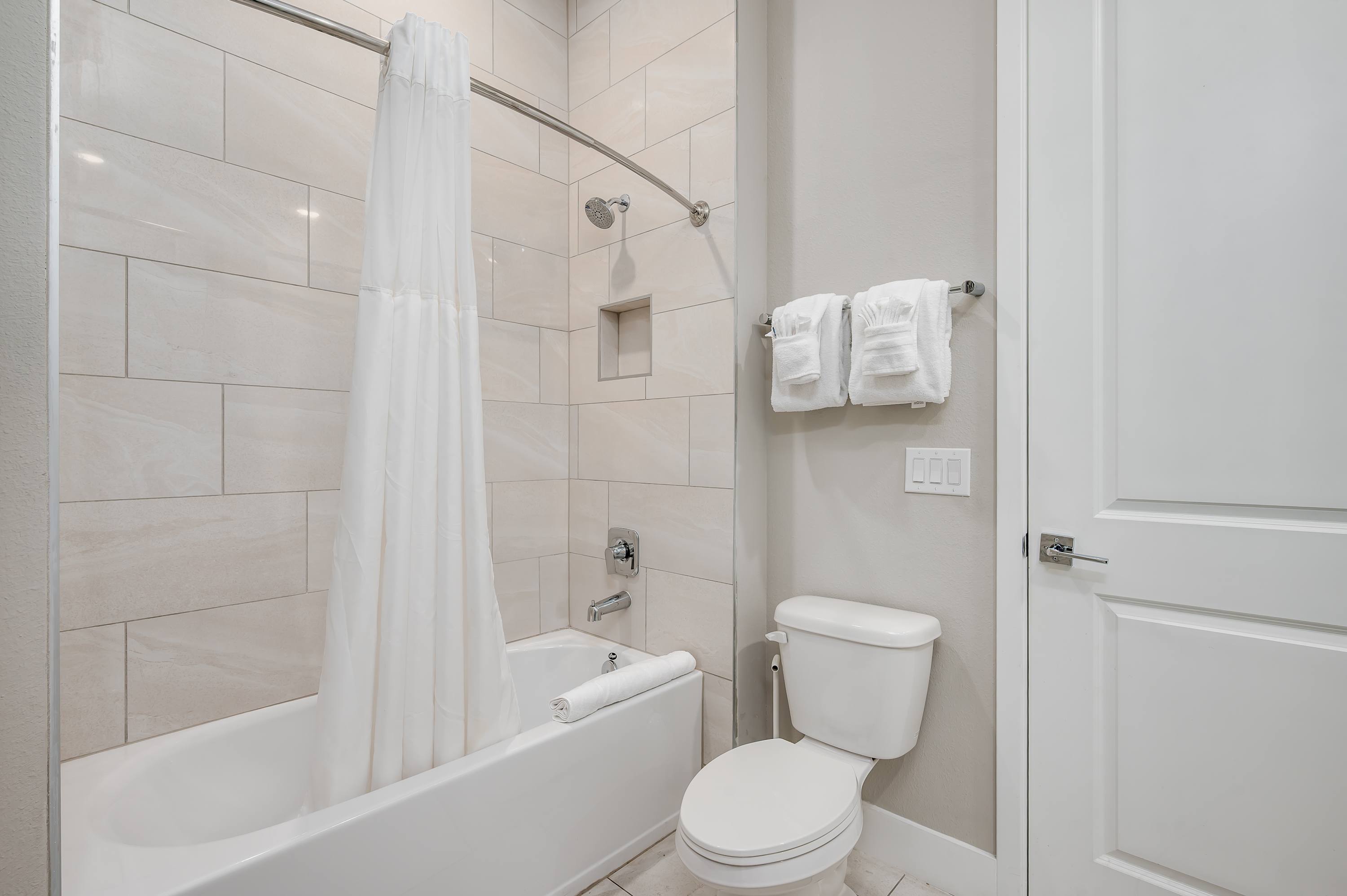 Modern bathroom with tiled shower and fresh white towels