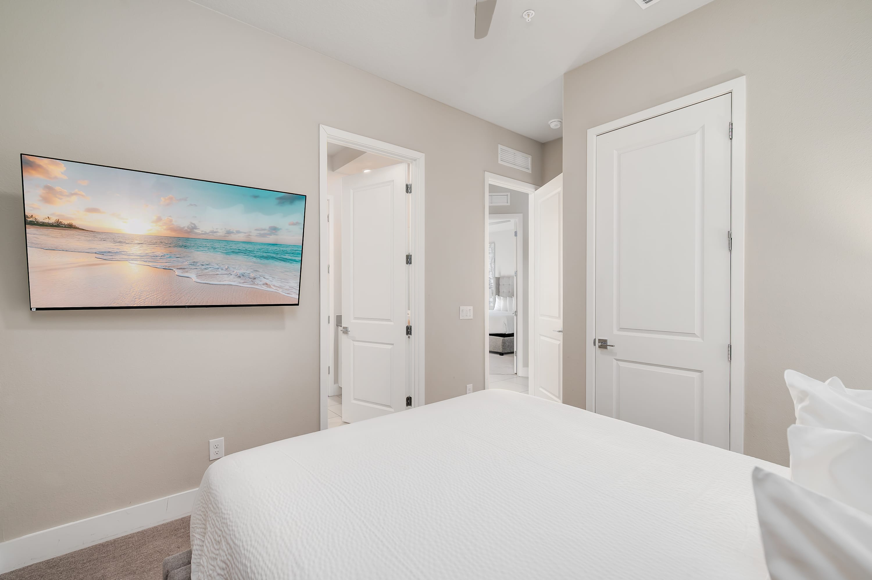 Modern bedroom featuring a wall-mounted flat-screen television and neutral tones.