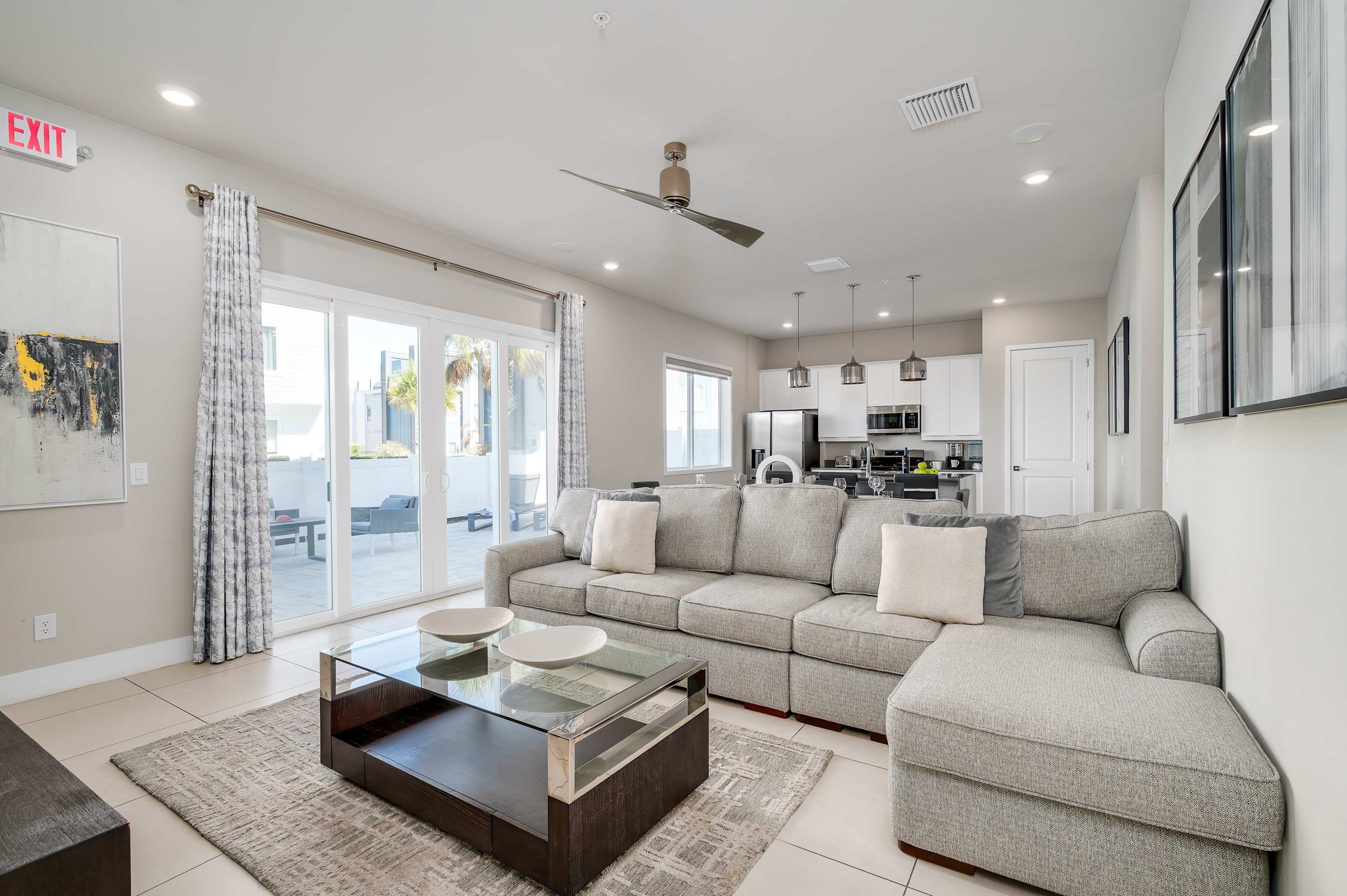Modern living room with a large sectional sofa and sliding glass doors leading to an outdoor patio.