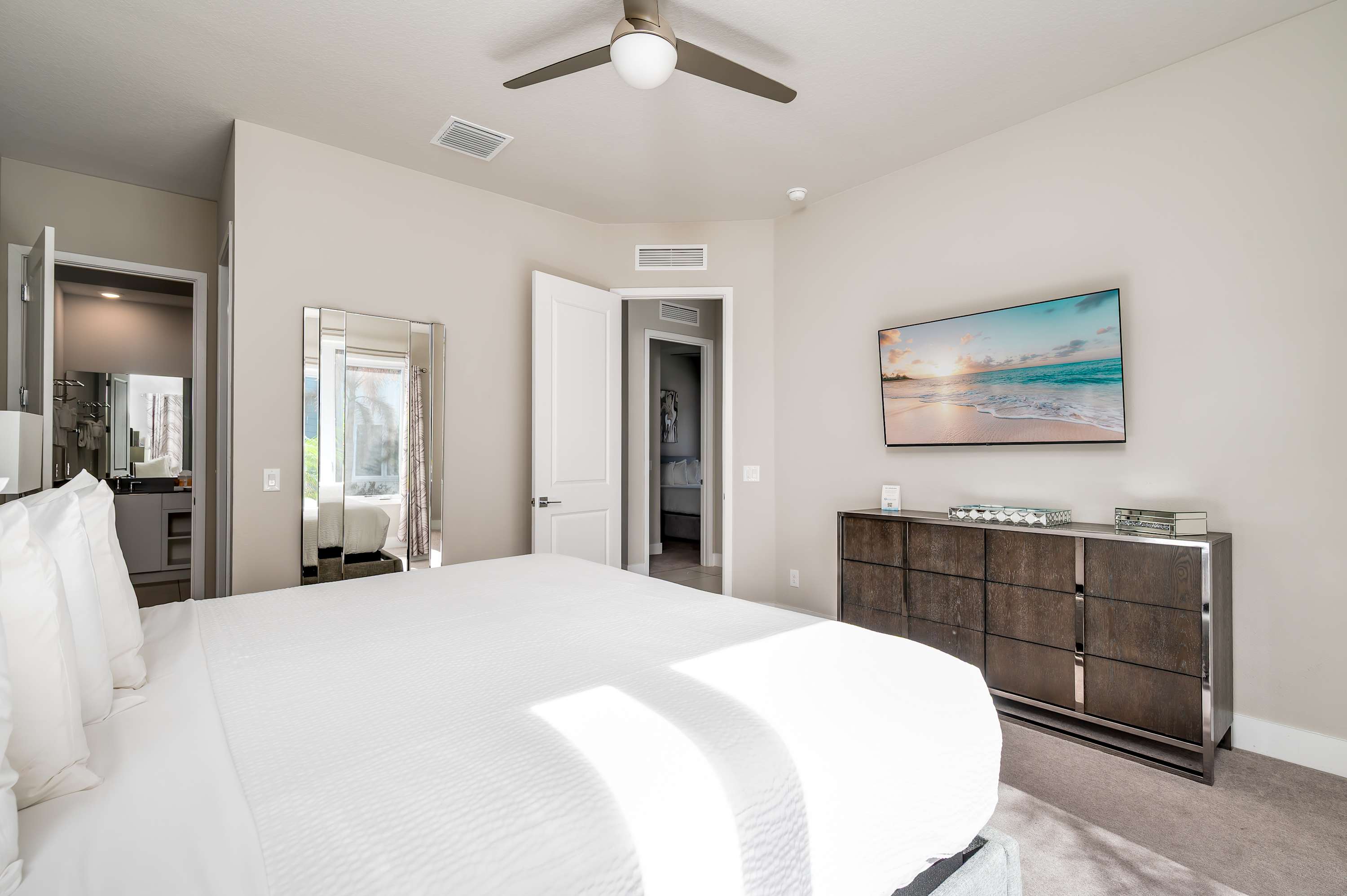 Bright bedroom with a ceiling fan and wall-mounted television for relaxing entertainment.