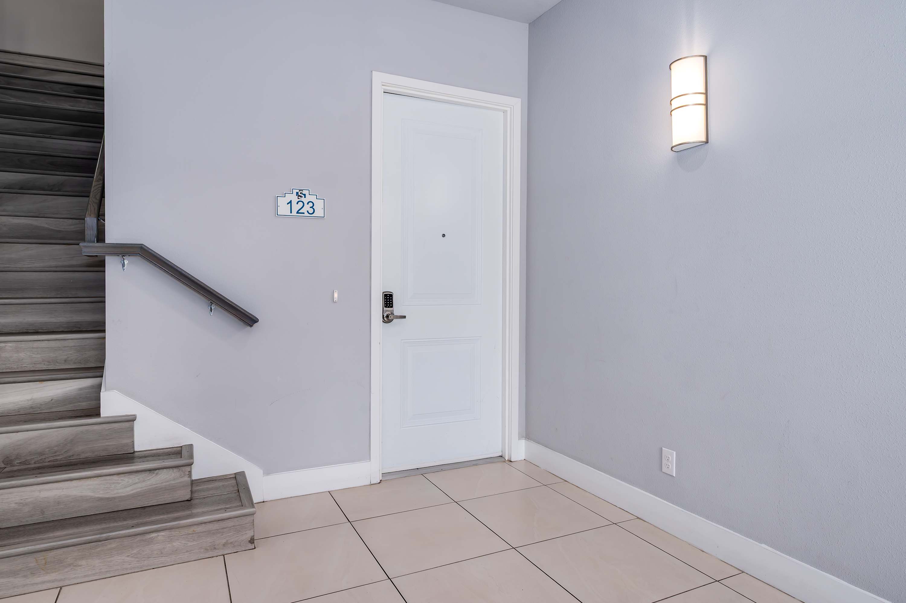 Entryway to unit 123 with modern keypad door lock and adjacent staircase.