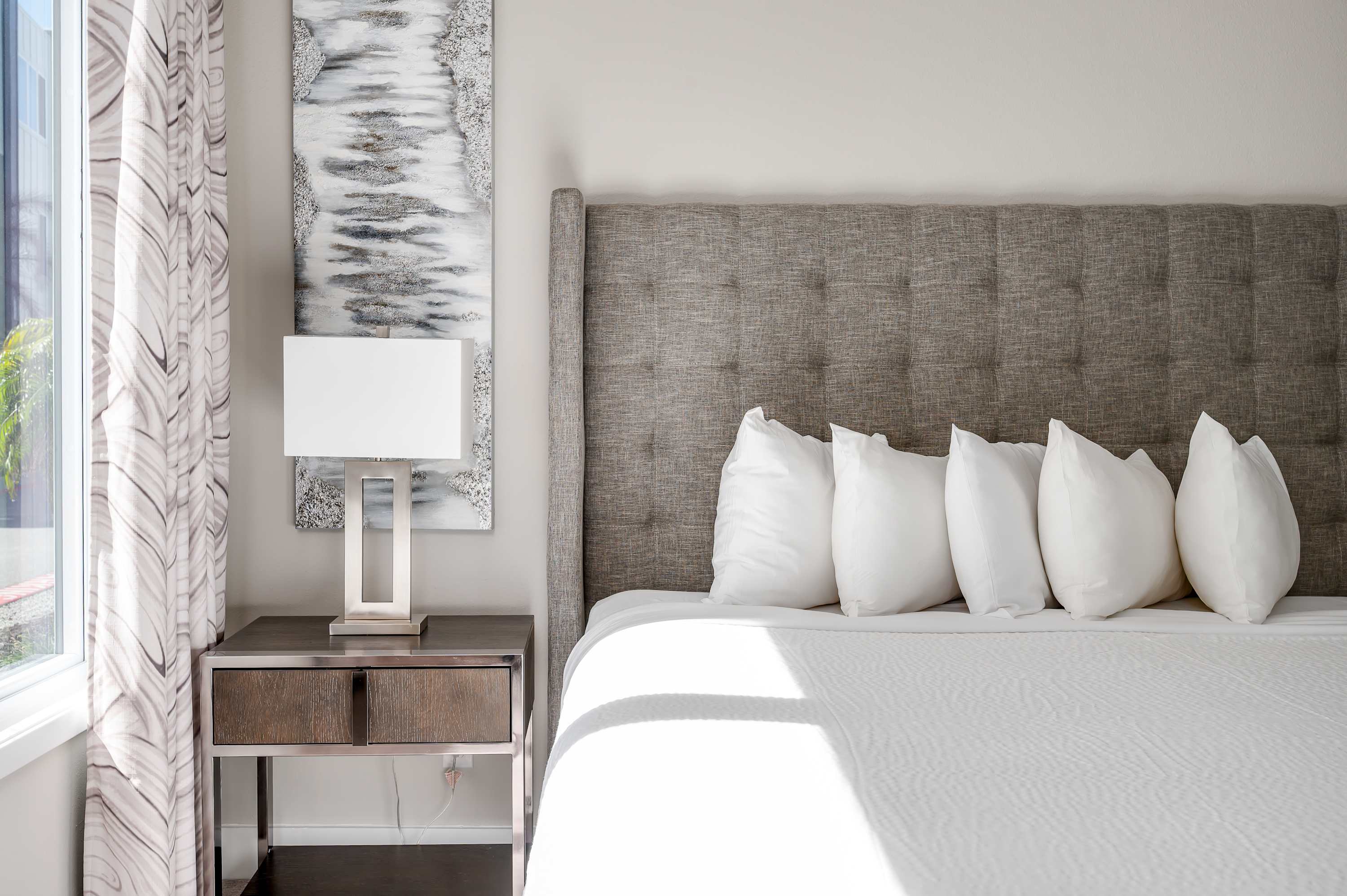 Modern bedroom with a textured gray headboard and natural light from the window