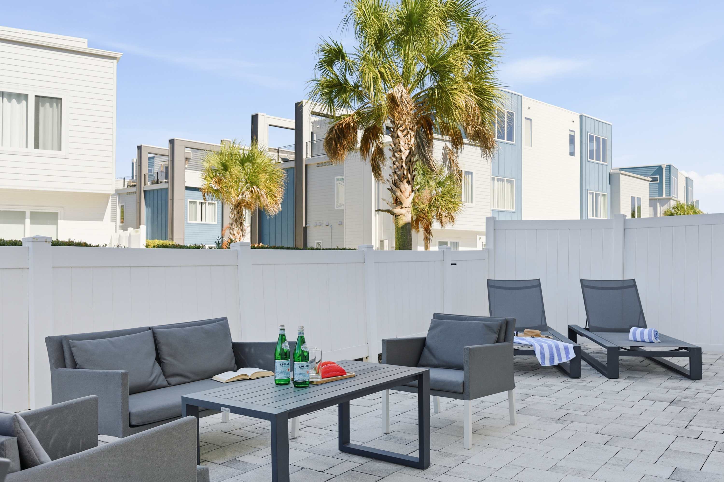 Modern outdoor patio with comfortable seating and palm trees in a sunny setting
