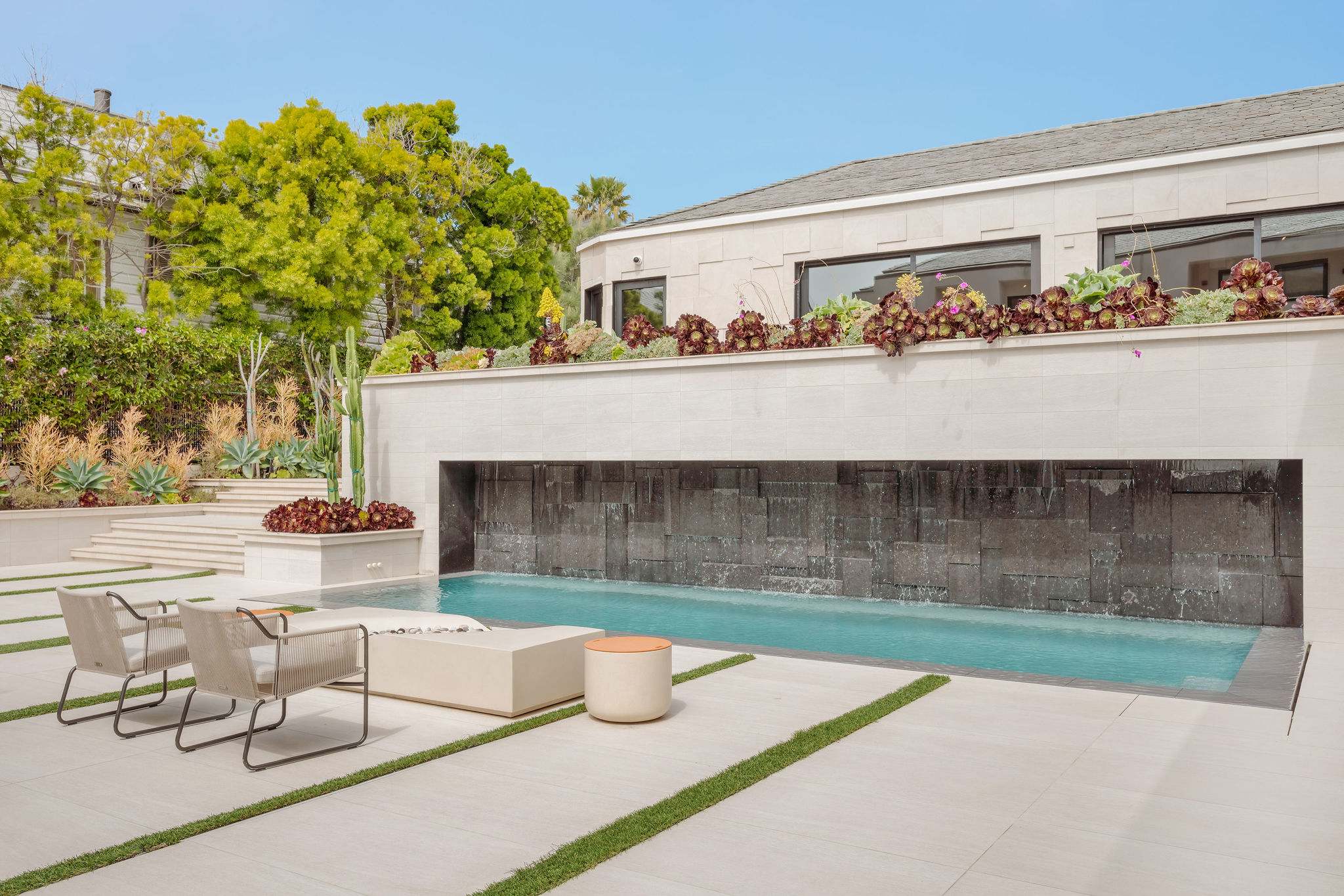 Architectural courtyard with water-wall feature and lounge seating.
