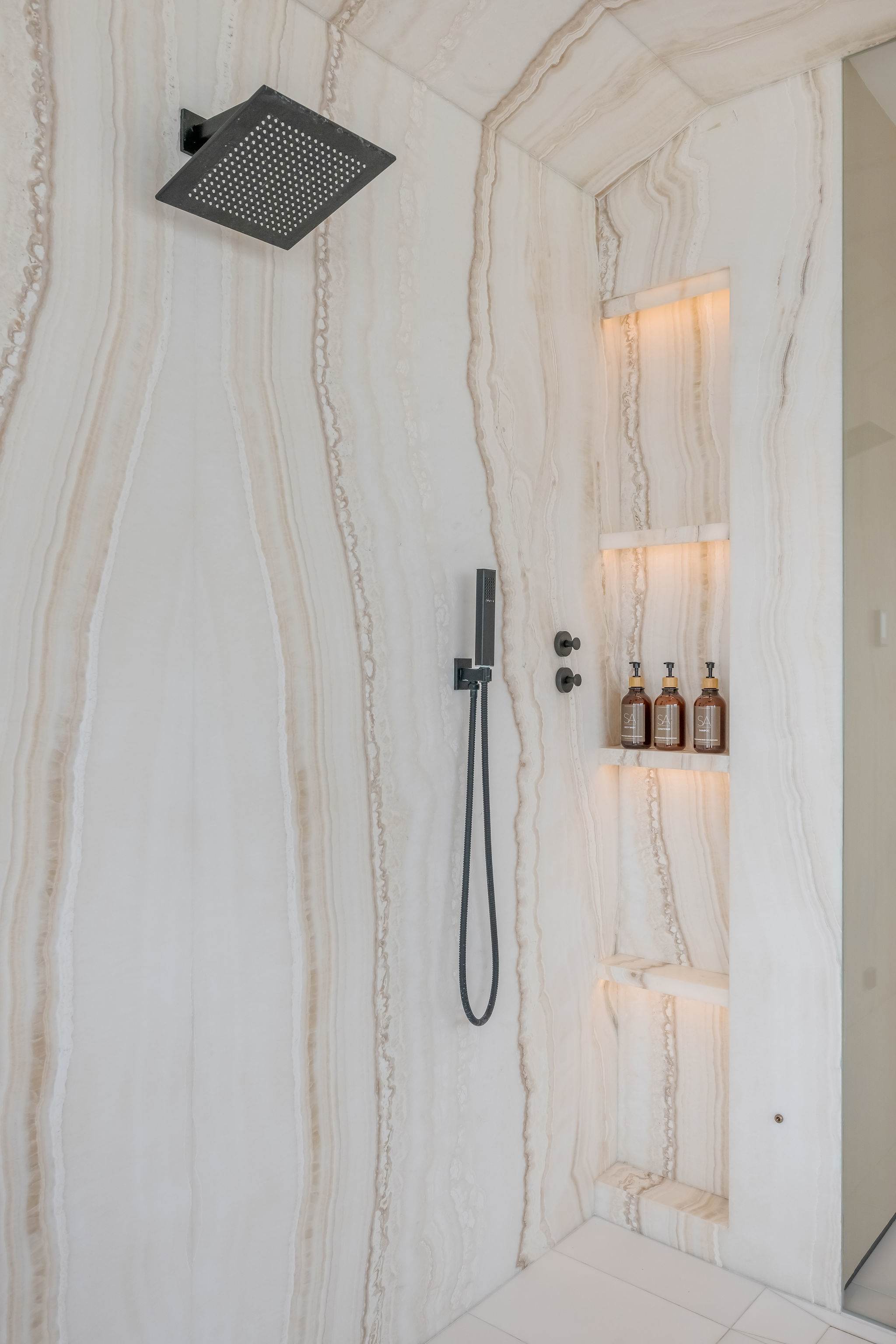 Walk-in shower with stone finishes and built-in niche detailing.