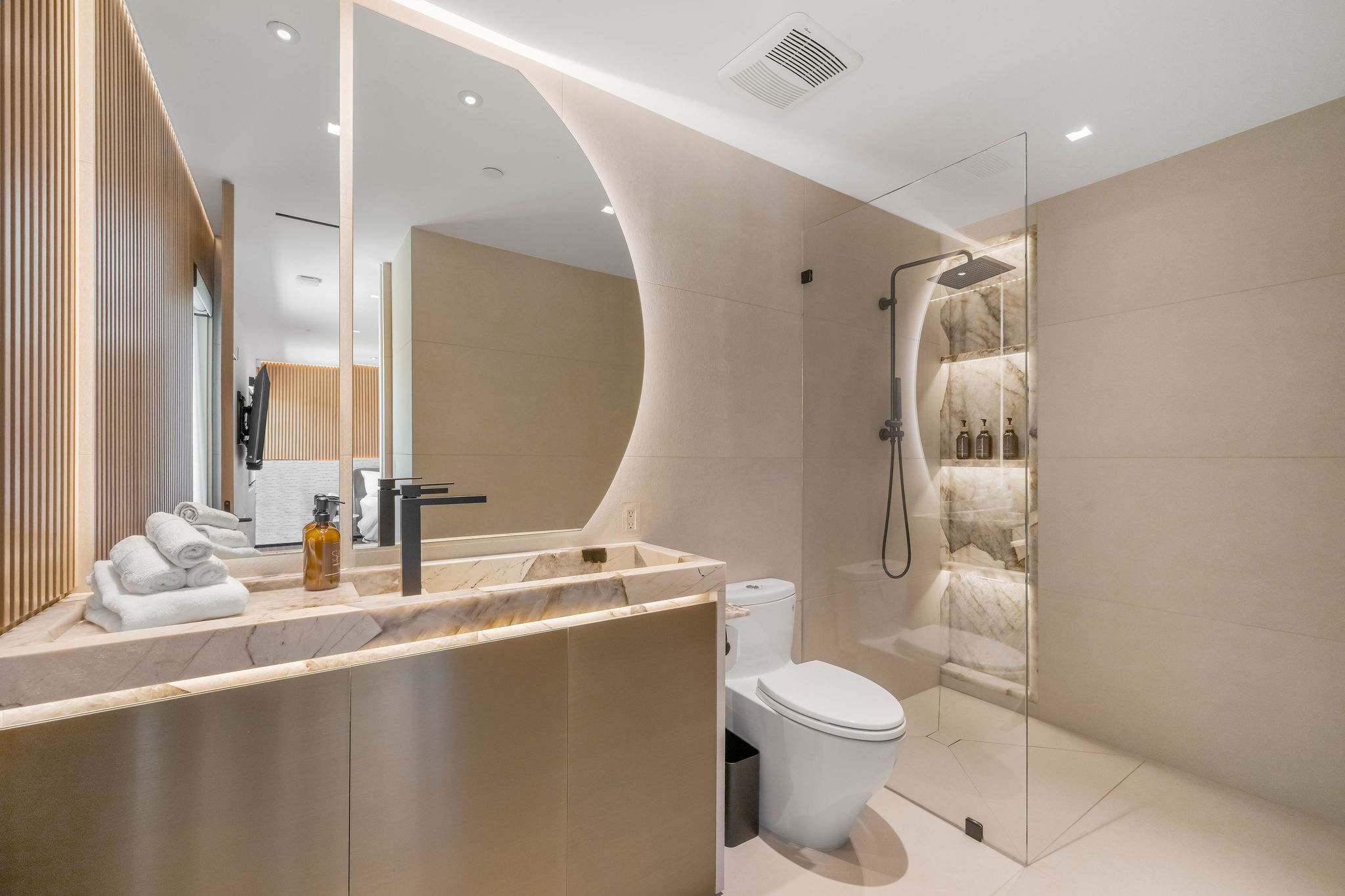 Designer bathroom with curved feature wall and integrated vanity.