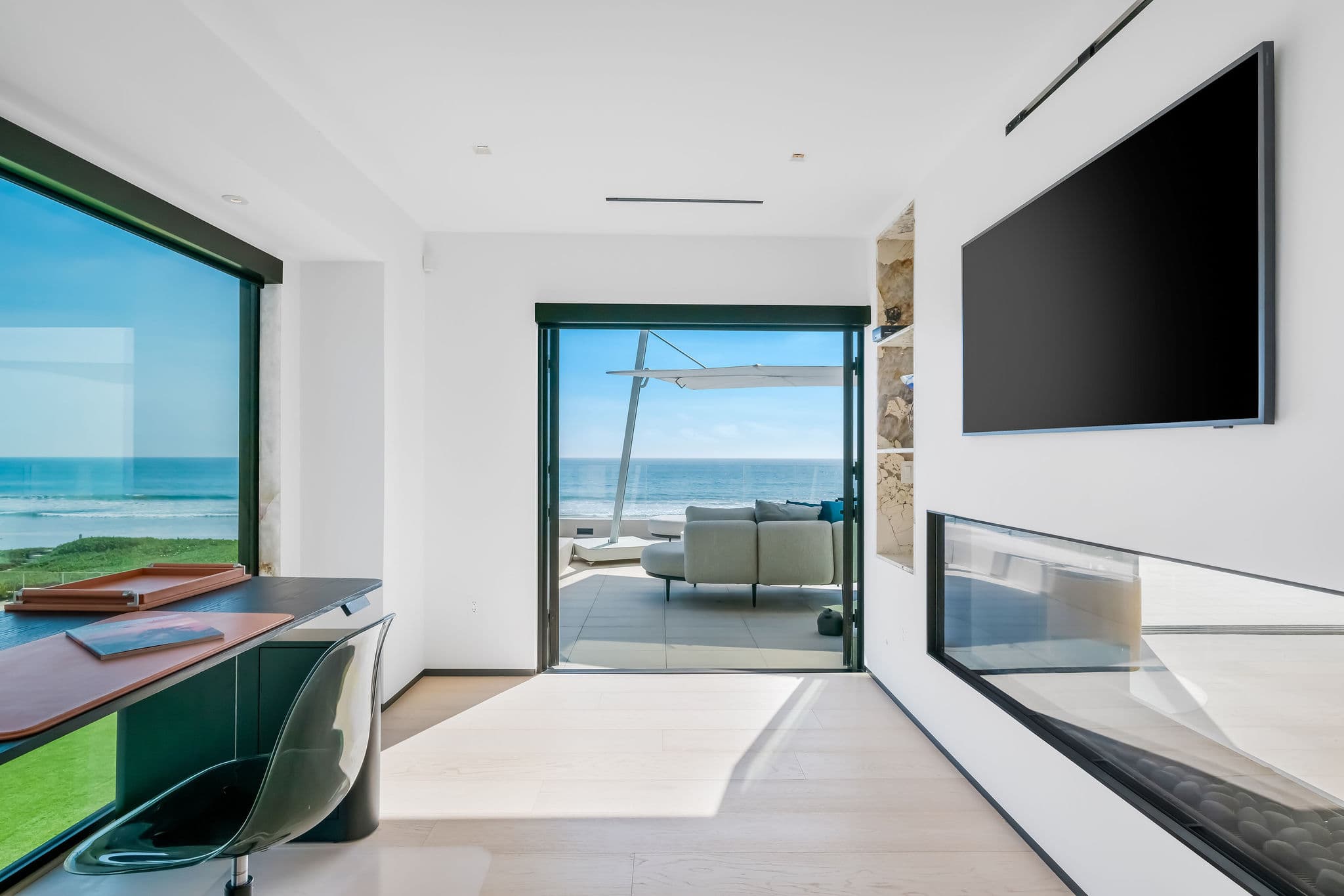 Private office with wall-mounted screen and direct access to oceanfront balcony.