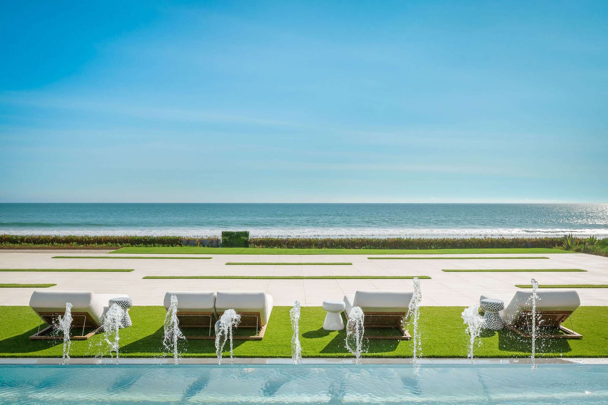 Oceanfront sun deck with aligned loungers facing the Pacific horizon.