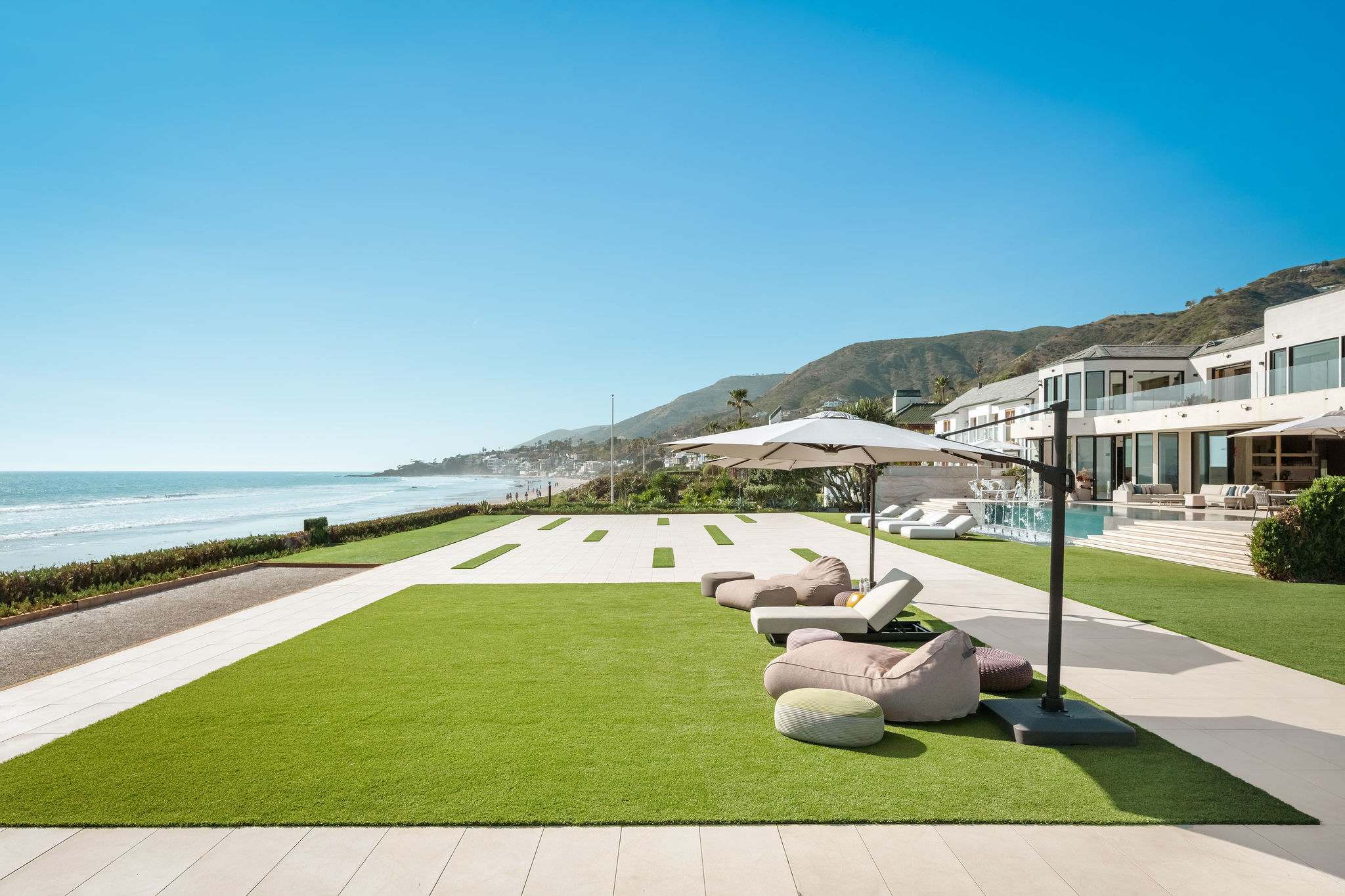 Oceanfront lawn with sculptural lounge seating and direct Broad Beach access.